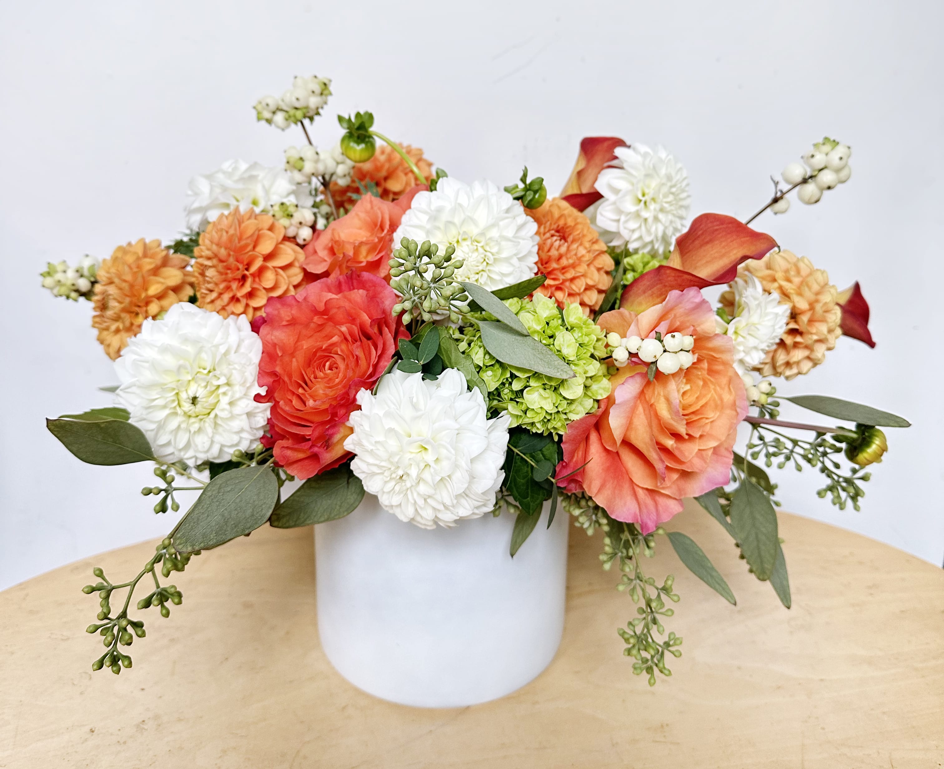 Dahlia Harvest Dahlia Harvest - This is a perfect gift for an early fall. This arrangement features white and orange New England dahlias, barries, orange free spirit roes and assorted greens.
