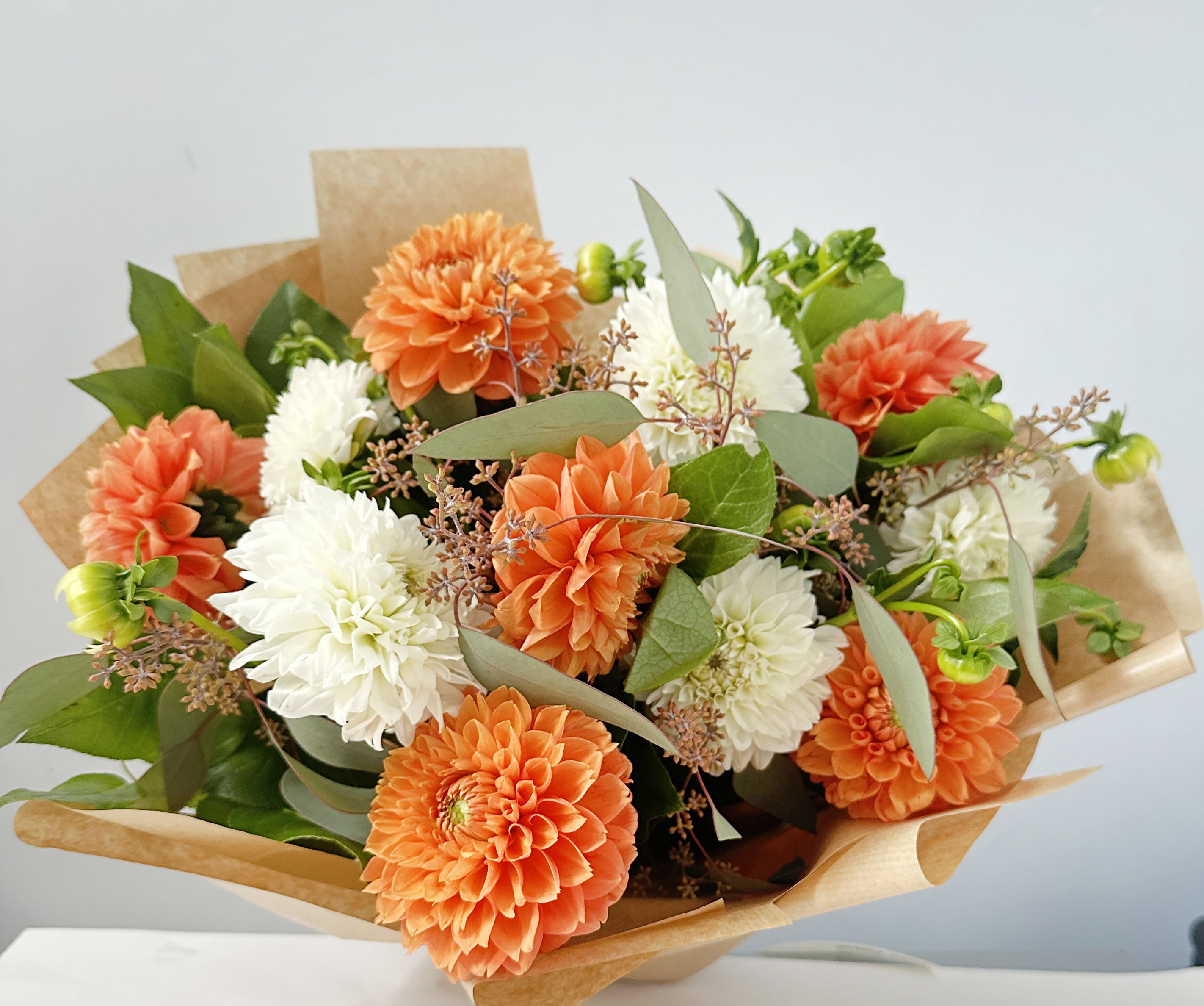 Dozen Dahlias Handtied Bouquet  - This standard size handtied bouquet includes a dozen mixed color dahlias with greenery. A deluxe size includes 2 dozen mixed color dahlias. A premium size includes 3 dozen mixed color dahlias 