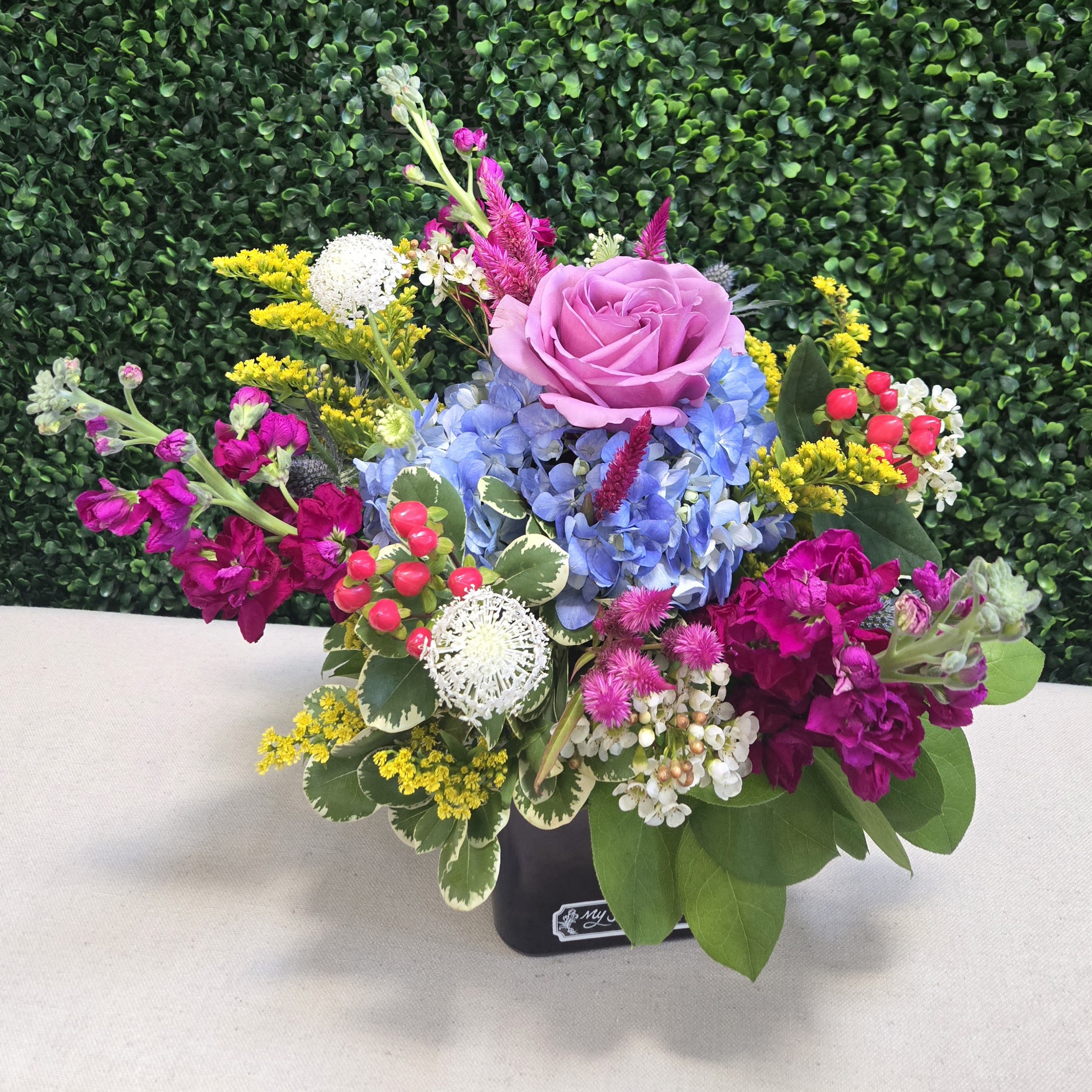 Summer Starlight - Summer Starlight is the perfect arrangement to add a unique glow to any warm summer night. Featuring fresh hydrangea, roses, stock, lace flower, and celosia grown in our own secret gardens. In shades of blue, pink, purple and white this stunning design will brighten any home or office space. 