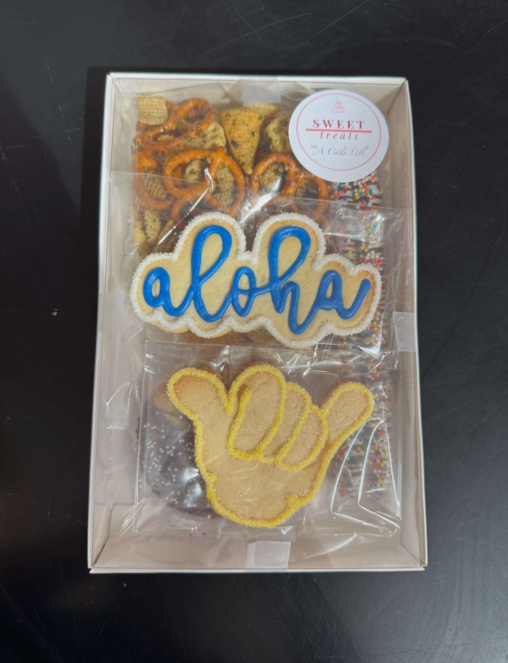 Sweet Treats Shaka Box (from A Cake Life) Sweet Treats Shaka Box (from A Cake Life) - Indulge in a delightful assortment with Cake Life's delicious box set, featuring 7 of their most popular treats! Each item is crafted with care to satisfy your sweet tooth and bring joy to any occasion. Whether as a gift or for indulging yourself, the Cake Life Box Set promises to delight with its variety of flavors and textures. Perfect for sharing at gatherings or enjoying a moment of sweetness.