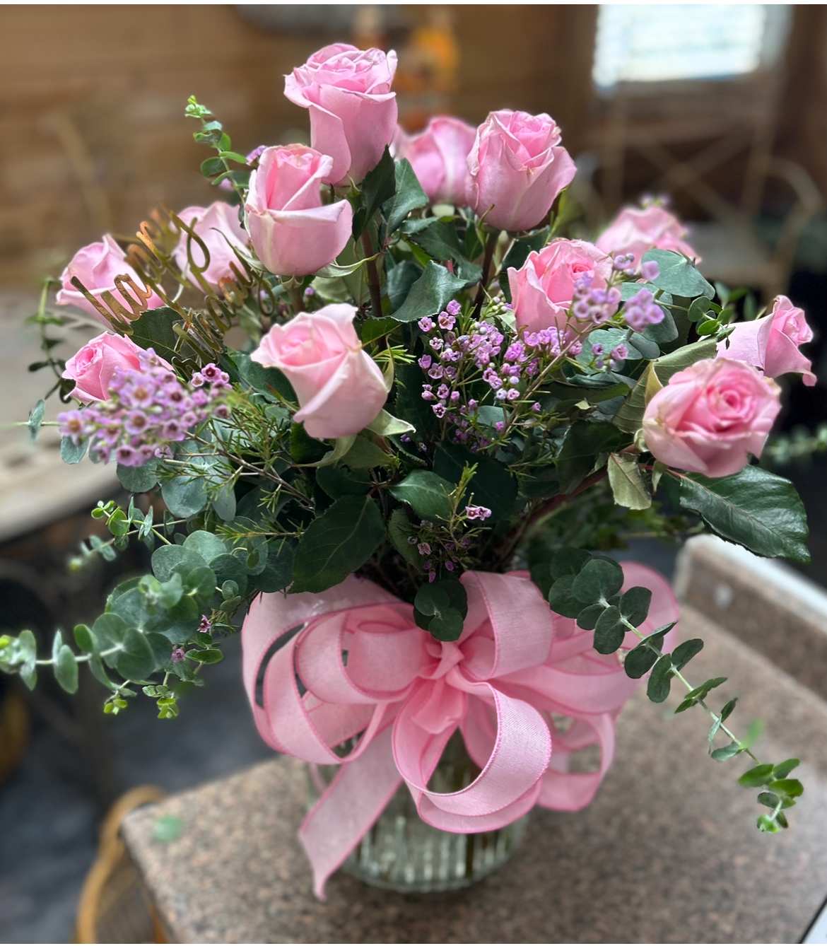 One Dozen Premium Pink Roses One Dozen Premium Pink Roses - Premium pink roses with premium green and filler flowers with a pink bow in a glass vase