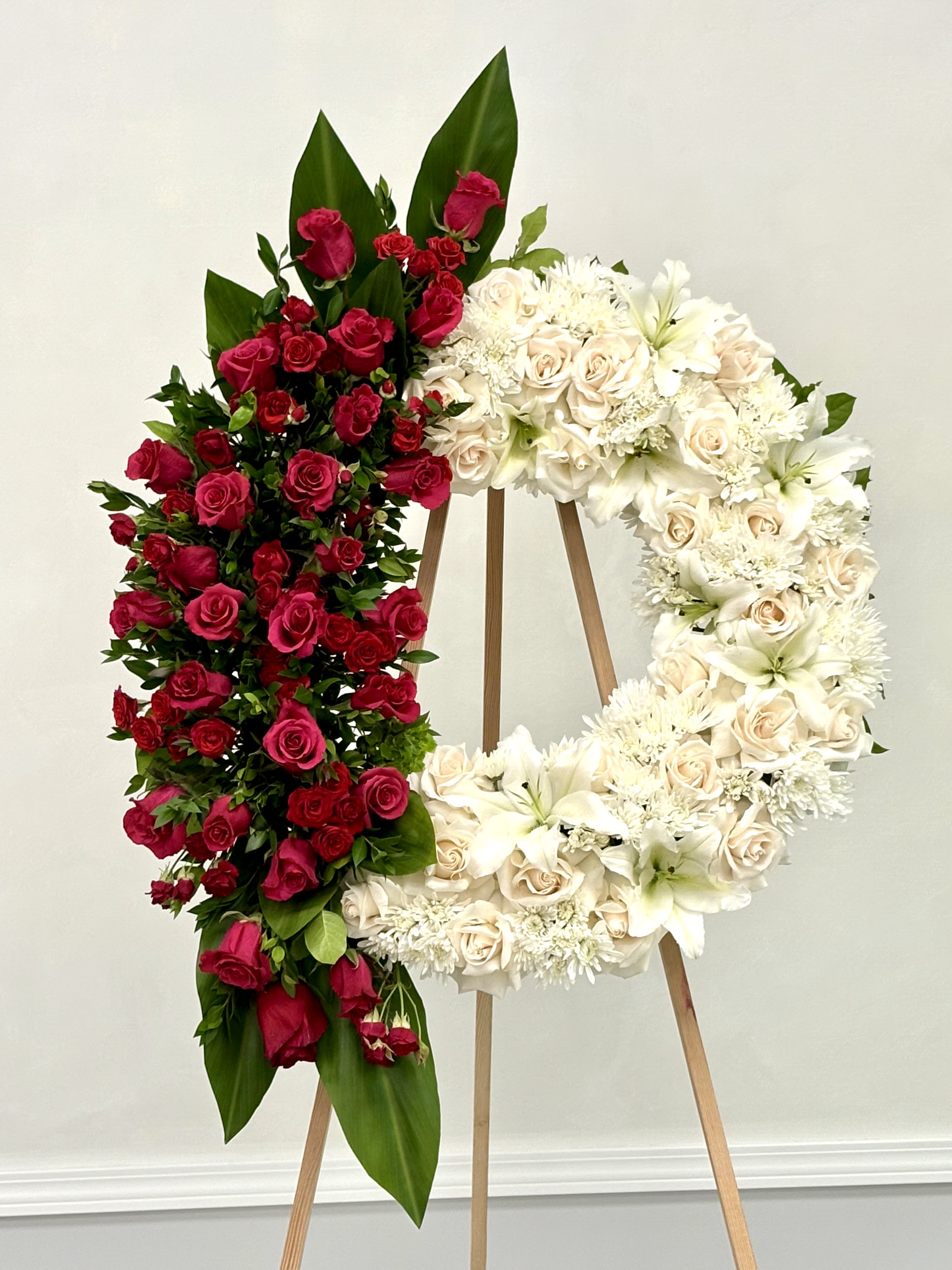 Circle of Remembrance By VLM Flowers Circle of Remembrance By VLM Flowers - A graceful wreath of pure white flowers accented with a striking red design. This timeless arrangement represents eternal love, peace, and honor — a beautiful tribute for memorials and funeral services.