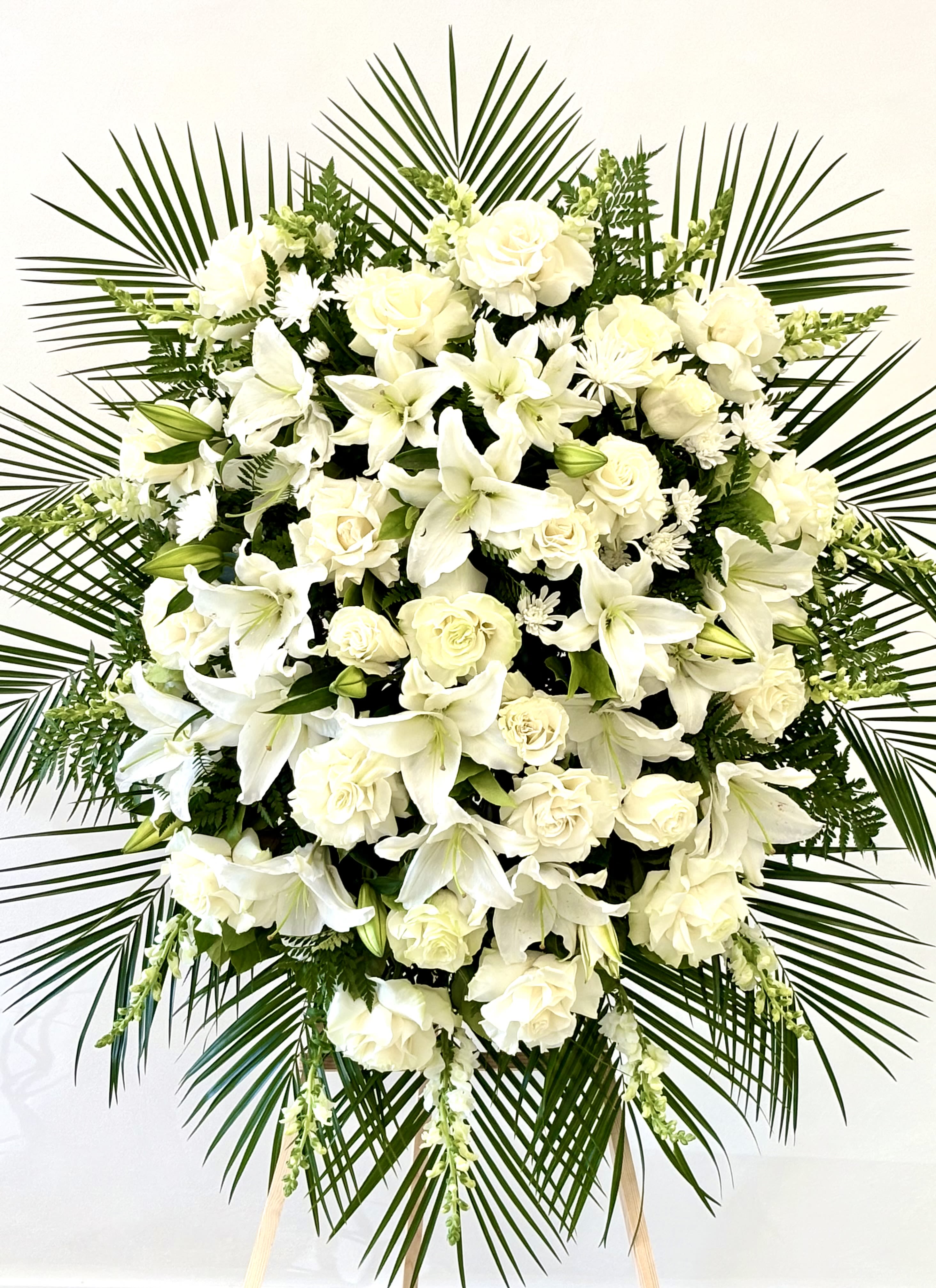 Heavenly Peace Spray By VLM Flowers - An elegant standing spray of white roses, lilacs, and snapdragons symbolizes purity, peace, and eternal love. This graceful tribute offers comfort and honor, making it a meaningful choice for memorial and funeral services.