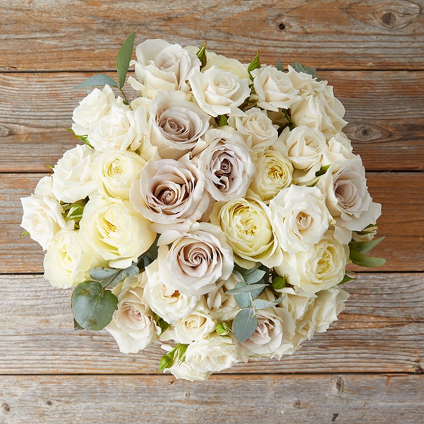 Whispered Elegance - A timeless bouquet of creamy white and soft roses, accented with eucalyptus, creating an elegant and romantic statement.