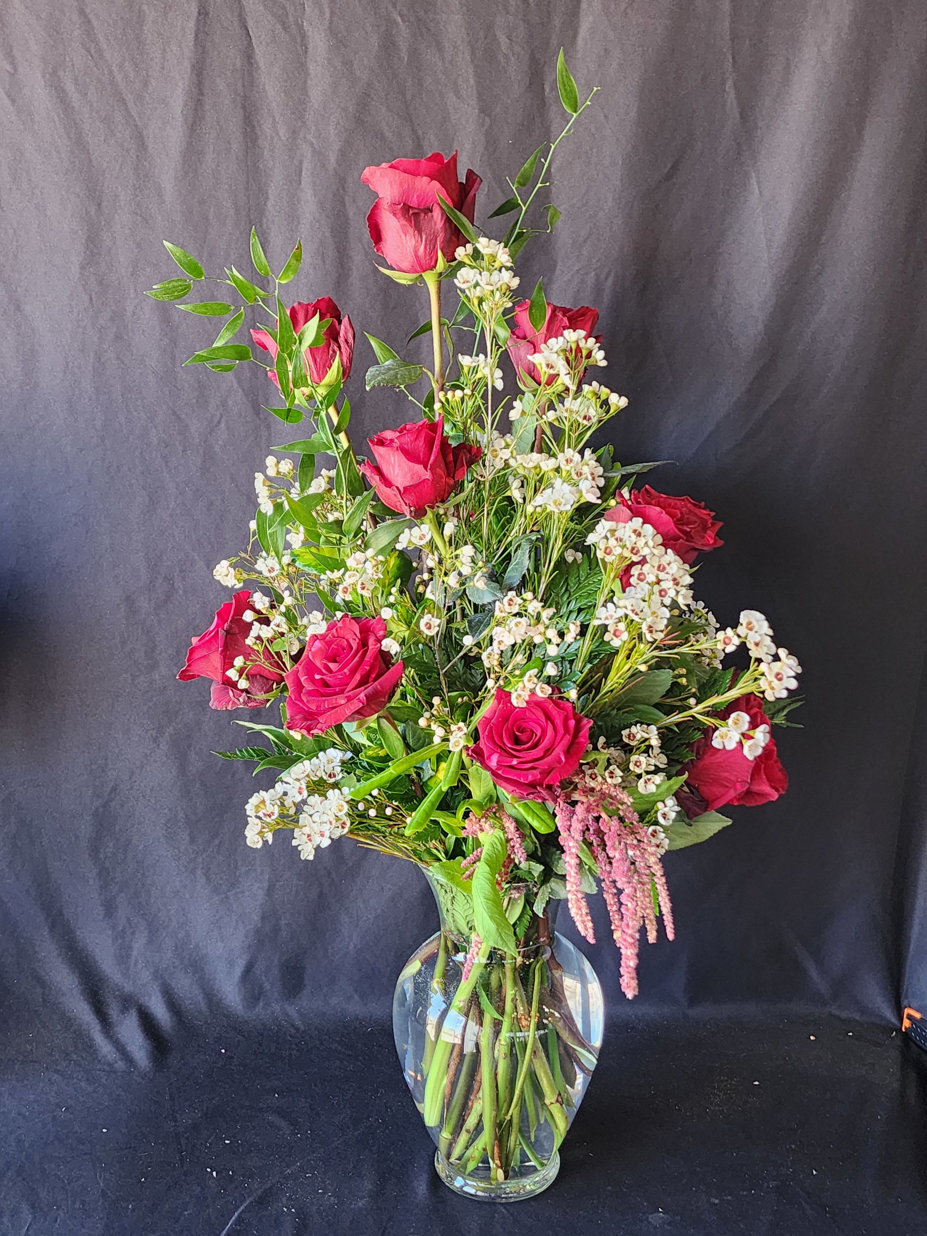  Roses by the Dozen - 1 dozen in a vase for the classic souls. Eriostemon (when available) foliage and Wax flowers  which has an incredible scent-citrusy &amp; fruity. Approximately 24&quot; high in an 8.5&quot; vase. Please call for other available colors. 2 dozen = Deluxe 3 Dozen = Premium