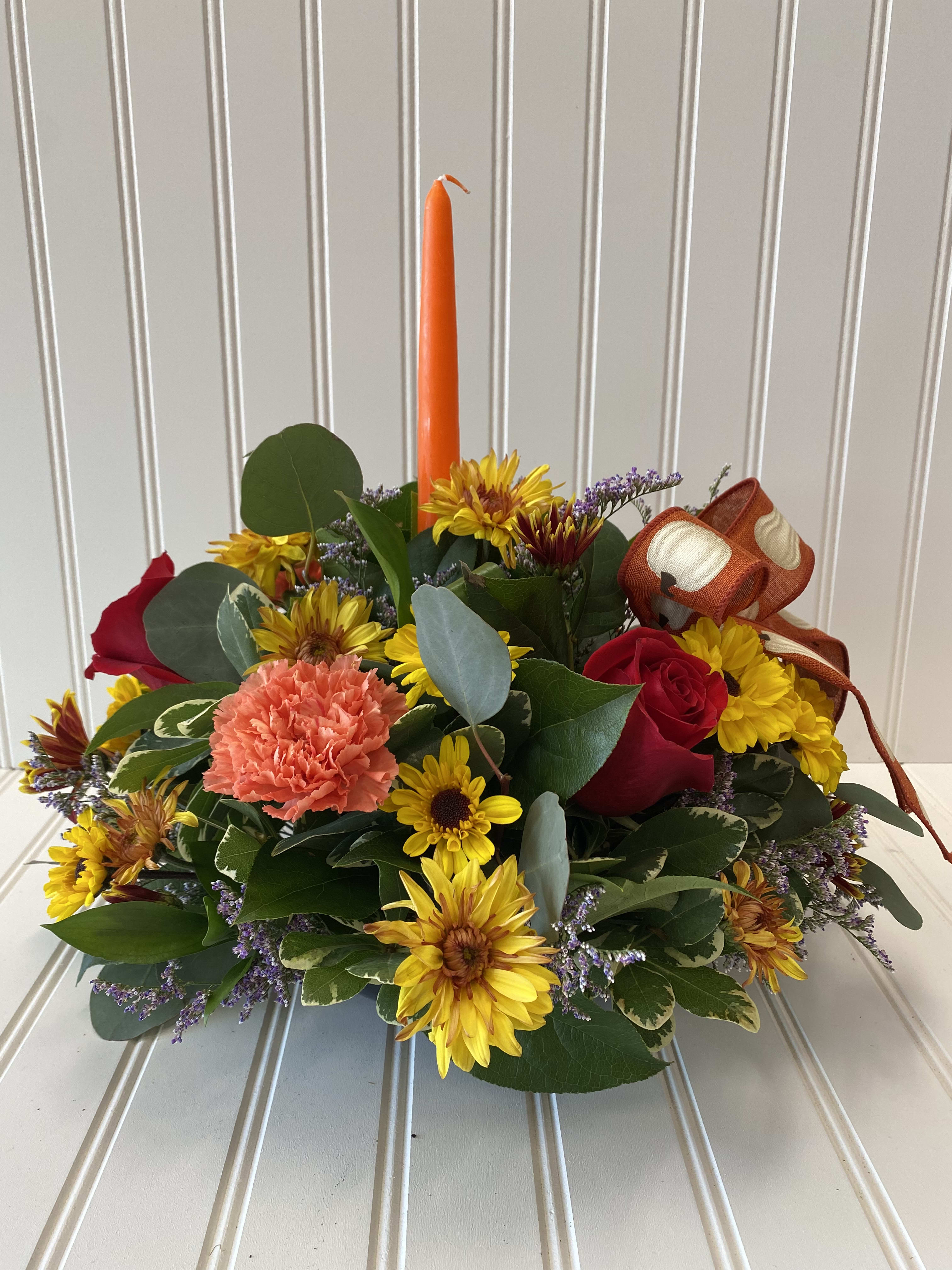 Traditional Thanksgiving Centerpiece 1  - This traditional centerpieces with one candle surrounded by rich fall flowers will surely dress any Thanksgiving table.