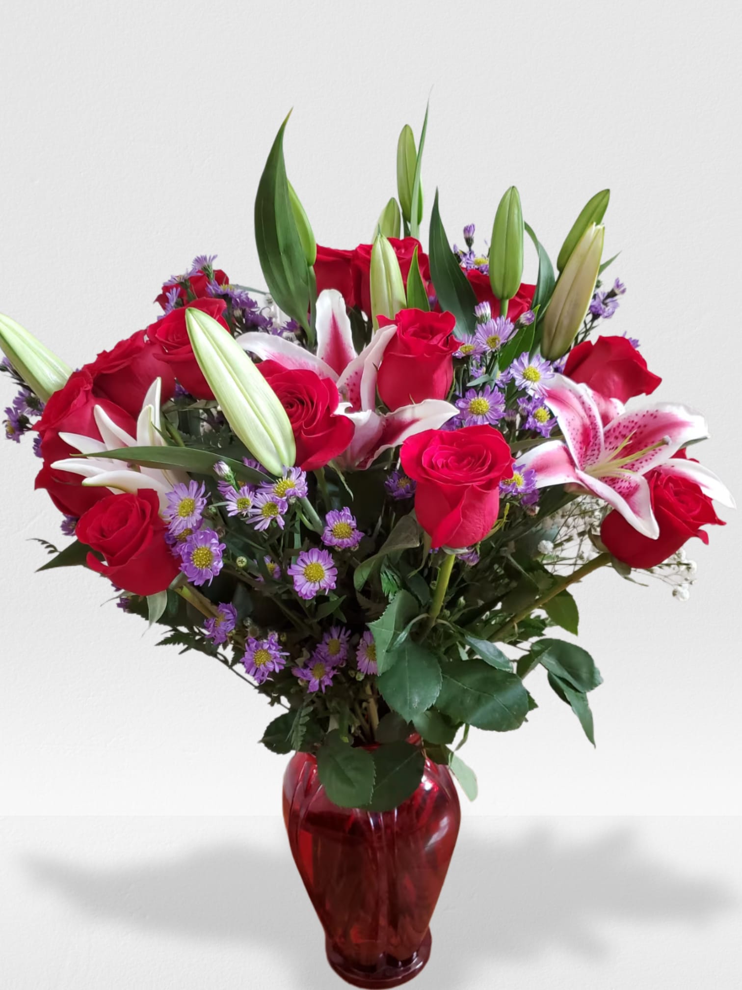 The best love - A beautiful vase arrangement in a red or clear vase 24 Rose's and 5 Stargazer lily's and purple monte casino 