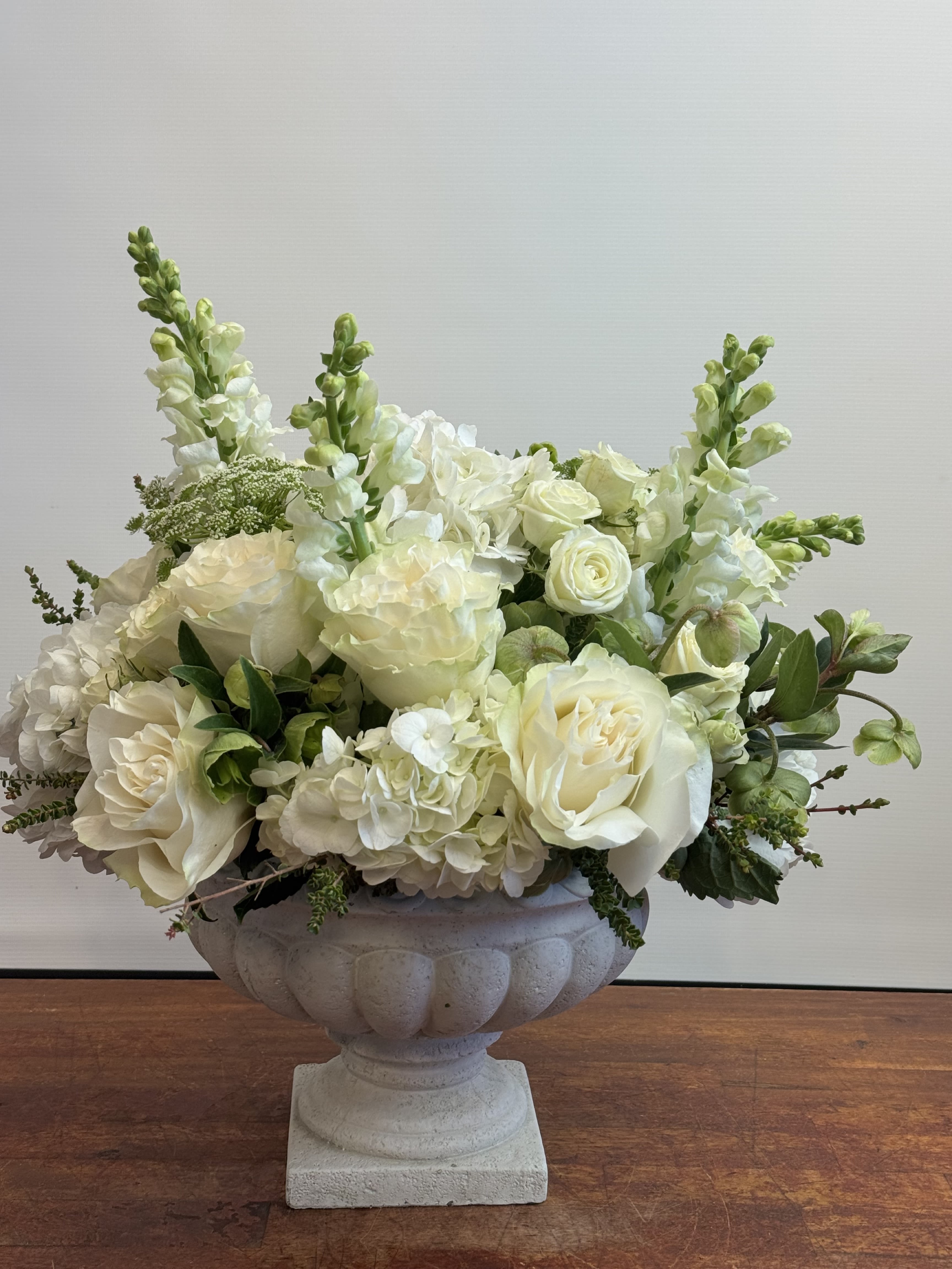Elegant White Floral Arrangement – Roses, Hydrangeas & Snapdragons in Classic Stone Vase Elegant White Floral Arrangement – Roses, Hydrangeas & Snapdragons in Classic Stone Vase - Bring sophistication and grace into any space with our Elegant White Floral Arrangement. Designed in a stone urn vase, this luxurious composition features creamy white roses, lush hydrangeas, and tall snapdragons, accented with delicate greenery. A versatile choice for weddings, celebrations, sympathy arrangements, or refined home décor, this arrangement embodies timeless beauty. Available for same-day delivery across Los Angeles with Sofi La Fleur’s signature care.