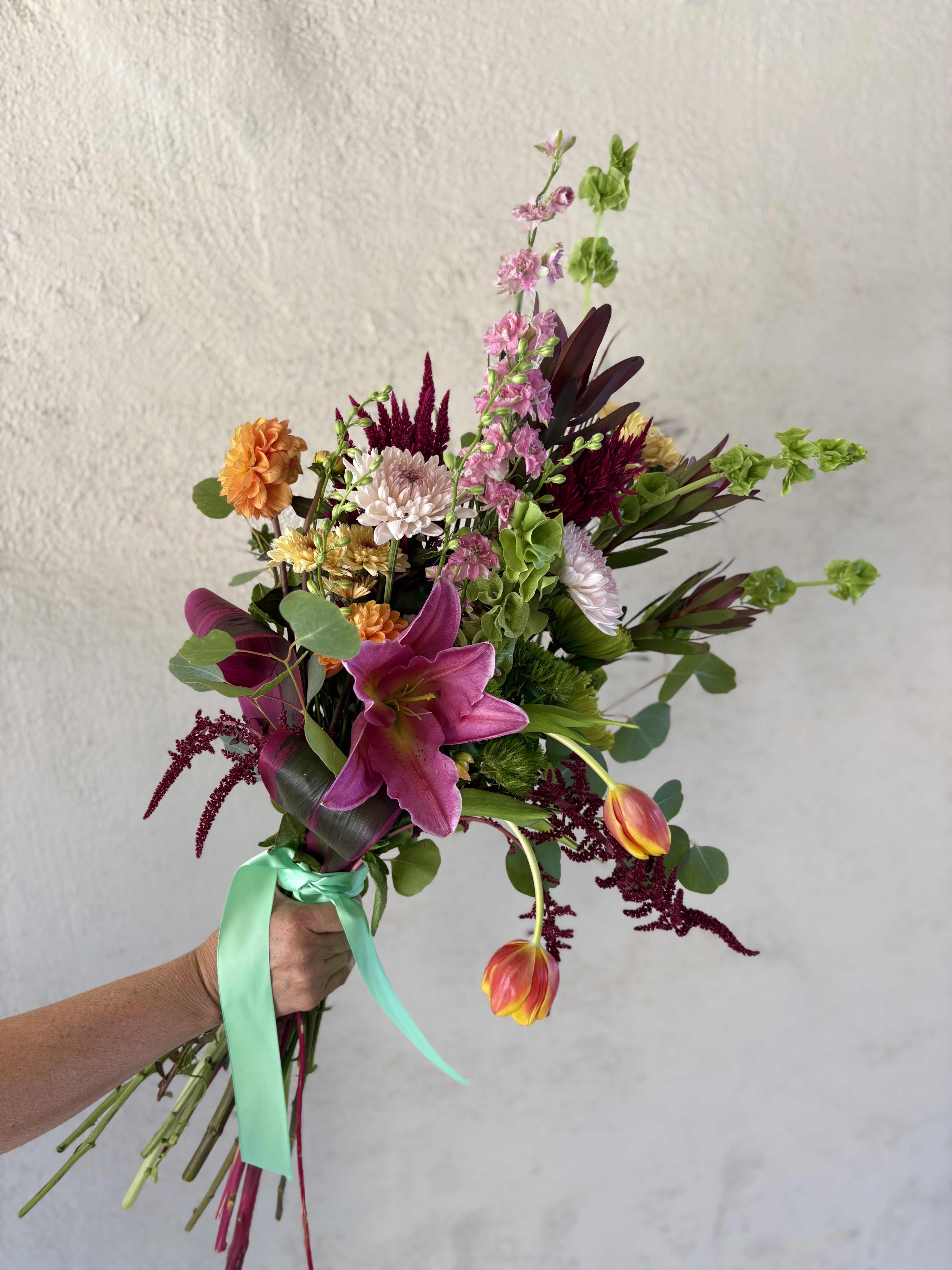 FRESH WEEKLY DROP - This weeks wrap includes pinks, greens, and oranges with Seasonal Dahlias, Amaranths, Larkspur, bells of ireland, Chrysanthemum Spray (Fuji and Cushion), Tulips, Dianthus, Stargazer, Safari, and so much more!