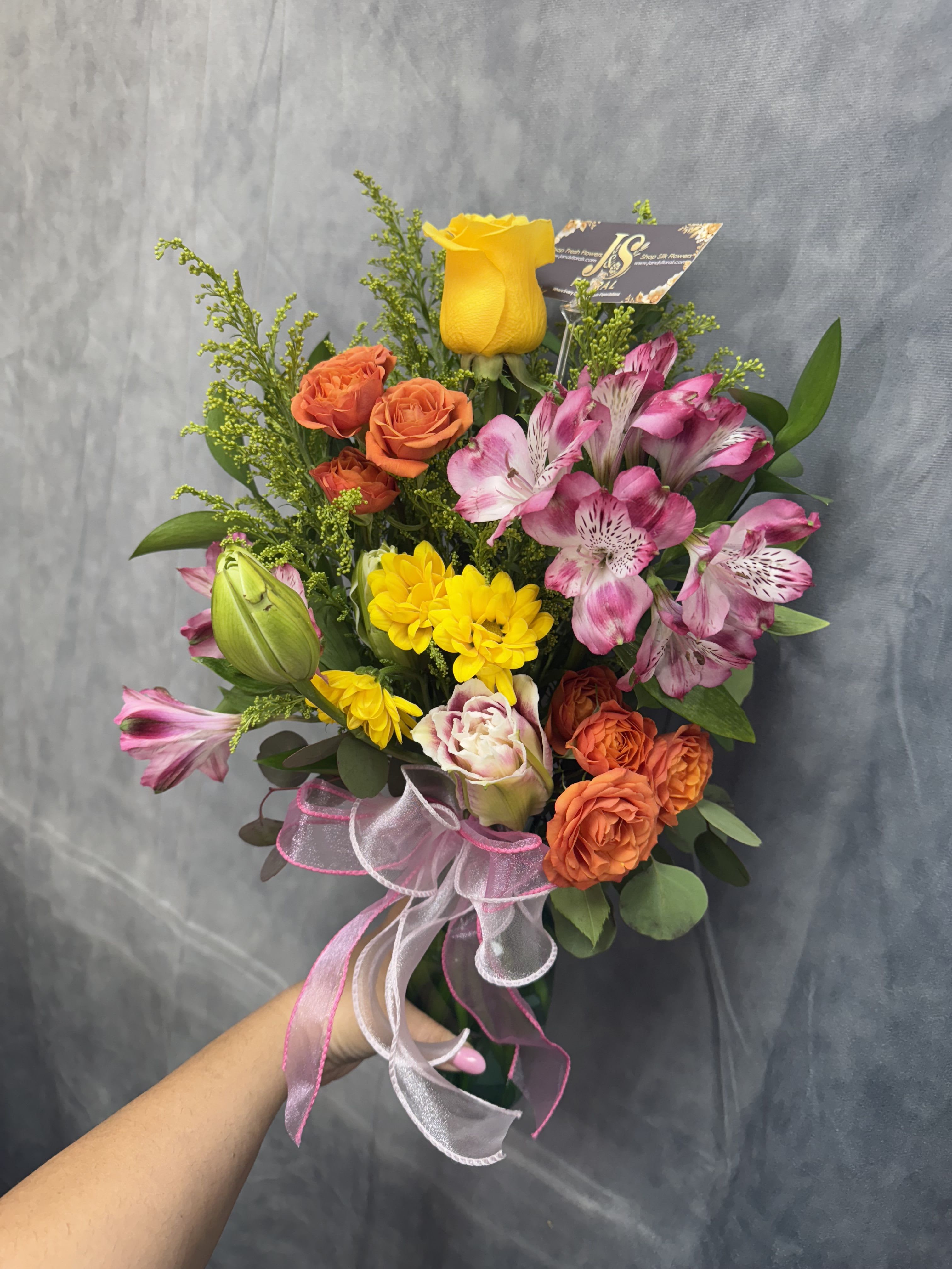 Sunset Glow Vase - A bright and cheerful small vase featuring warm orange lilies, lively orange spray roses, sunny yellow roses, and soft pink alstroemeria — a perfect burst of color to light up any room.