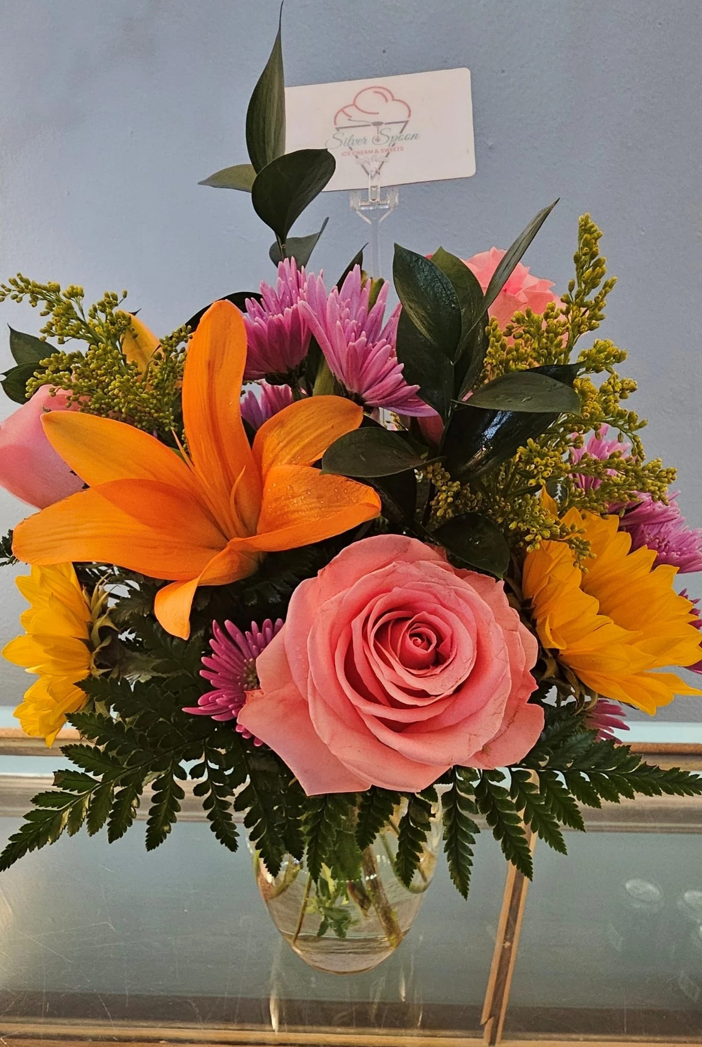 Sweet as Sugar - A perfect pairing! Ice Cream and Flowers!  A vibrant flower bouquet with a rich gathering of yellow and orange blooms, with pops of bright pink and purple combined with a $15.00 gift card to Silver Spoon Ice Cream! The only World Award Winning, super premium scooped Ice Cream in Missouri. 2 locations to serve you. 