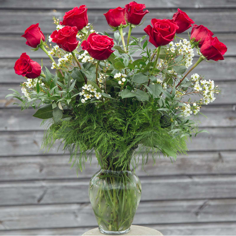 Dozen Premium Red Roses - One dozen long stem red roses with wax flower and tree fern in a glass vase. 