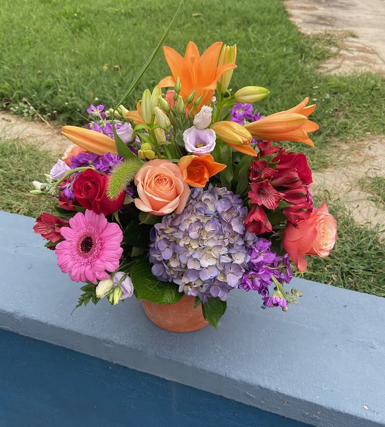 Terra Cotta Garden Terra Cotta Garden - Orange lilies, red and orange roses, purple stock, red alstro, pink gerbera daisies, and purple hydrangeas sprout out of a terra cotta planter giving a burst of floral brightness to any occasion!