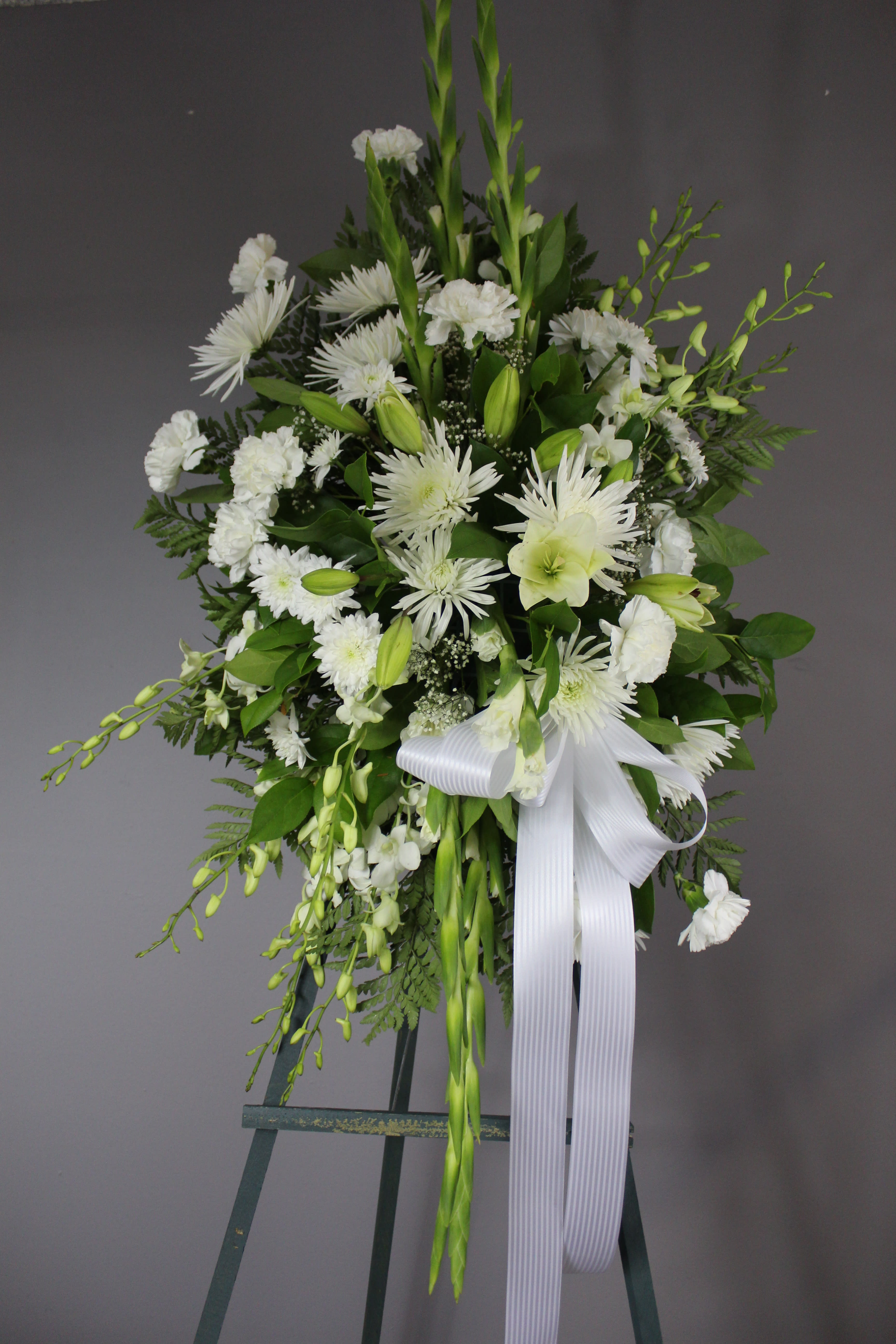 FUNERAL STANDING SPRAY - Sweet Memories - This is a wonderful option for a funeral service, church or graveside . This Standing spray is a one sided flower arrangement on a 5' easel (easel included) displaying a spray approximately 3’5” tall and 2' wide. This lovely mix of white flowers of lilies, fuji mums, carnations and gladiolas is the perfect way to send your condolences any time of the year.    **This is a piece for a funeral or memorial service. Please place the order at least 2 days prior to the service to guarantee a certain arrangement. Anything sooner and we cannot guarantee it will match the picture. These pieces can be customized to the color of your choice. The flowers may vary depending on availability of the flowers, special requests and quality of the flowers we have in stock. If you have a special request please add it to our special instructions when placing your order. If you have any questions please don’t hesitate to call. 714 289 1123**