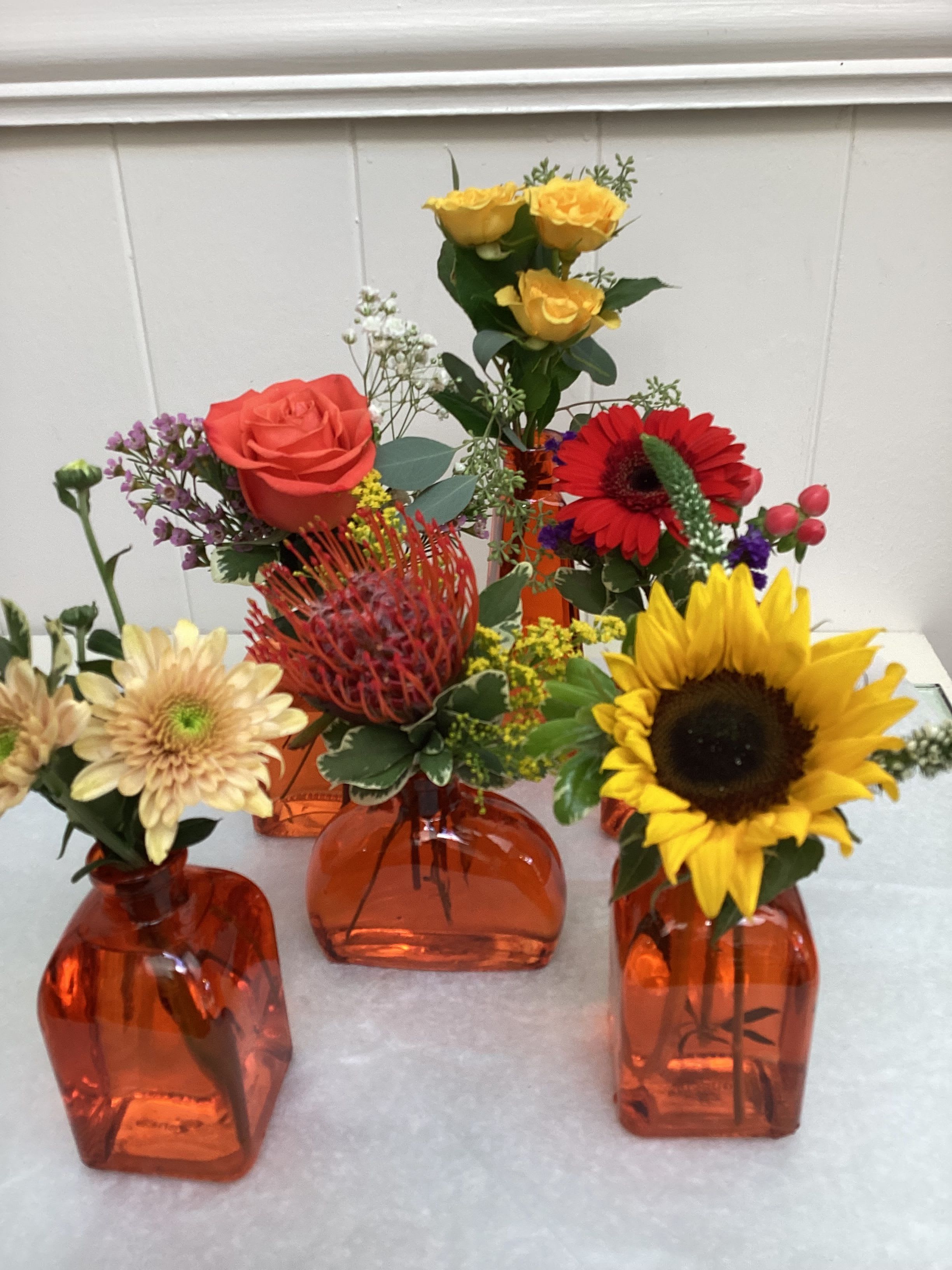 Kaleidoscope! - Six charming assorted orange colored vases, each accented with a different flower, filler, and greens or eucalyptus - like a kaleidoscope. No two collections are alike. Shown are six charming vases with flowers, Deluxe is nine wonderful assorted vases &amp; flowers. Premium is twelve fabulous vases &amp; flowers. 