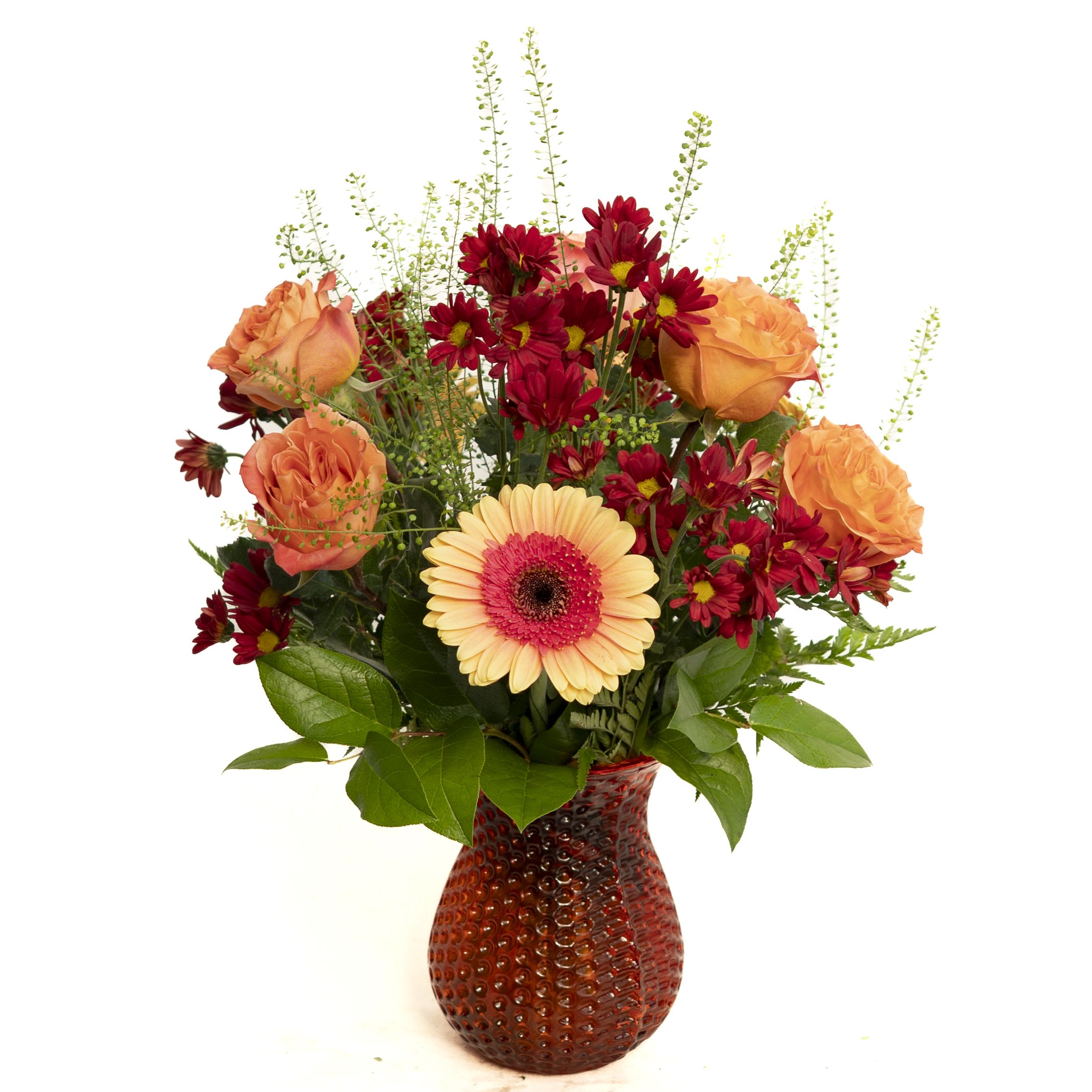 Autumn Glow - Bright and cheerful, the Autumn Radiance Bouquet features a warm blend of orange roses, deep red daisy poms, and a striking peach gerbera daisy accented with fresh greenery. Arranged in a textured orange glass vase, this design brings a cozy seasonal charm, perfect for adding a burst of color to any room or gifting to someone special.