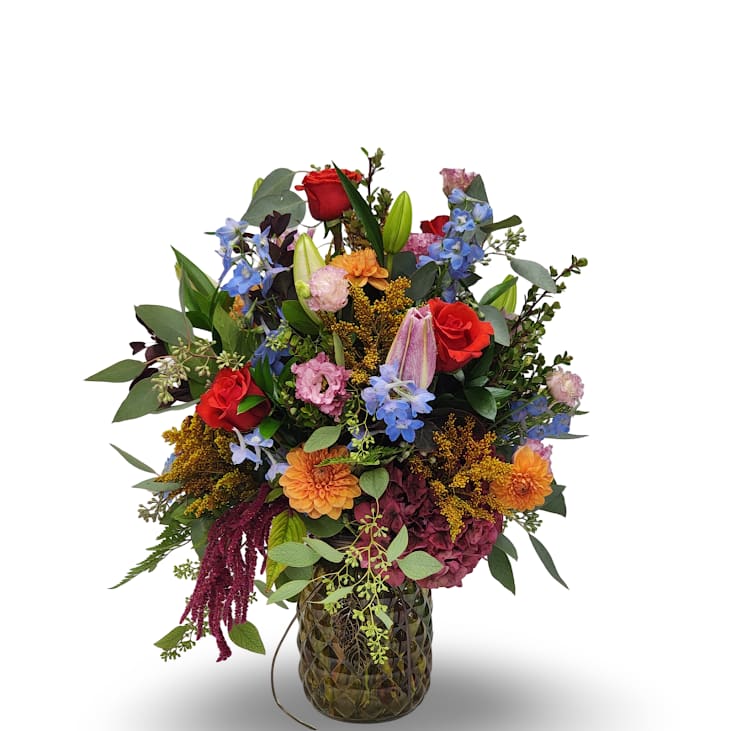 Autumn Symphony Autumn Symphony - This vibrant arrangement overflows with rich seasonal color, blending roses, lilies, delphinium, hydrangea, and other fresh blooms for a lively and abundant look. Designed to be enjoyed from every angle, it stands approximately 23 inches tall by 17 inches wide, making it a stunning centerpiece or display piece for any occasion.