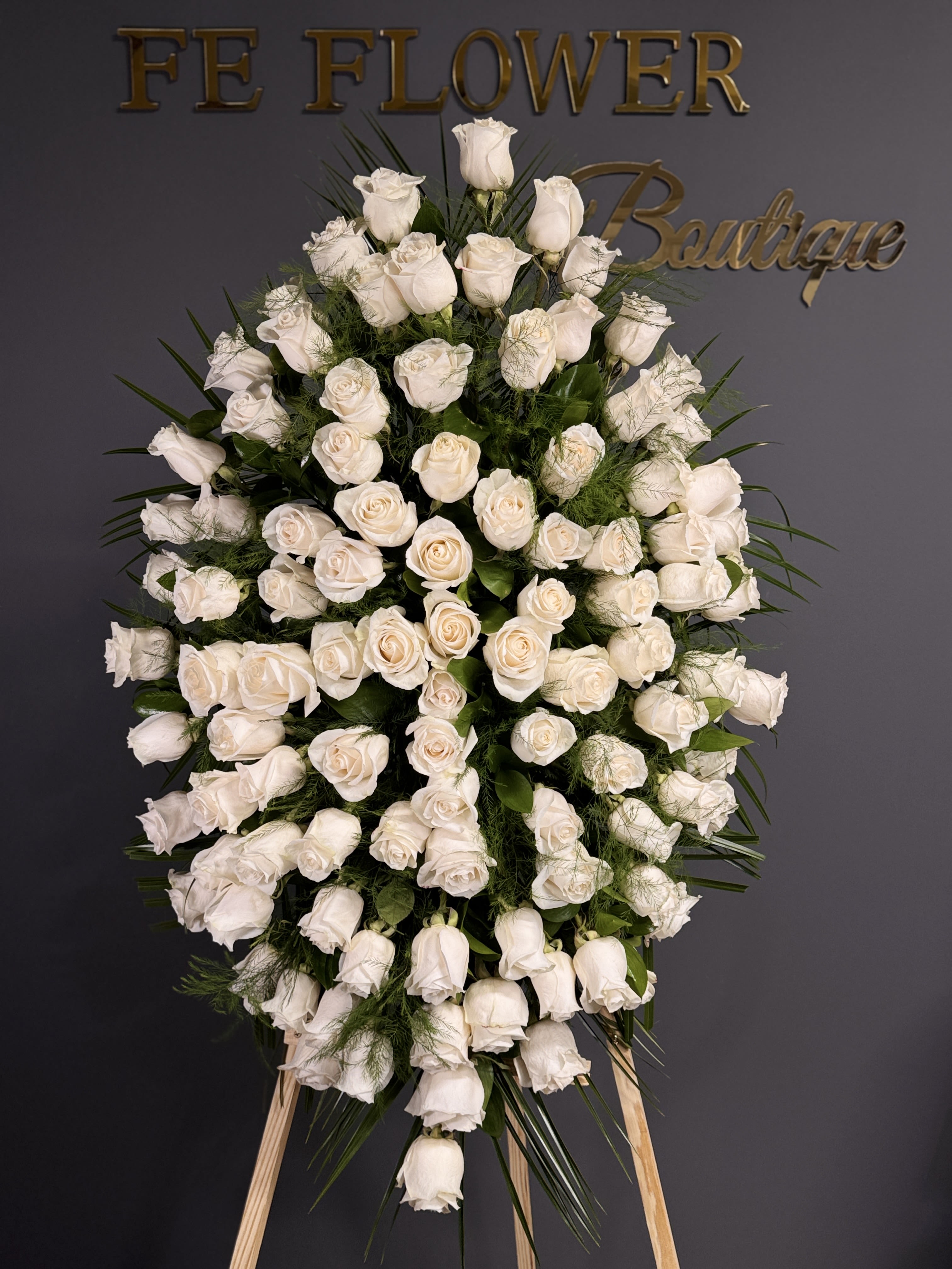 Eternal Grace - A breathtaking display of serenity and honor, Eternal Grace is a standing floral tribute composed of 100 pristine white roses, carefully arranged with elegant greenery and lush foliage. This grand and dignified piece expresses heartfelt sympathy, respect, and eternal remembrance.  Symbolizing peace, purity, and unconditional love, this design serves as a powerful final tribute for memorial services, funerals, or to convey profound condolences. Standing tall with reverence, it's a timeless gesture of grace and devotion.