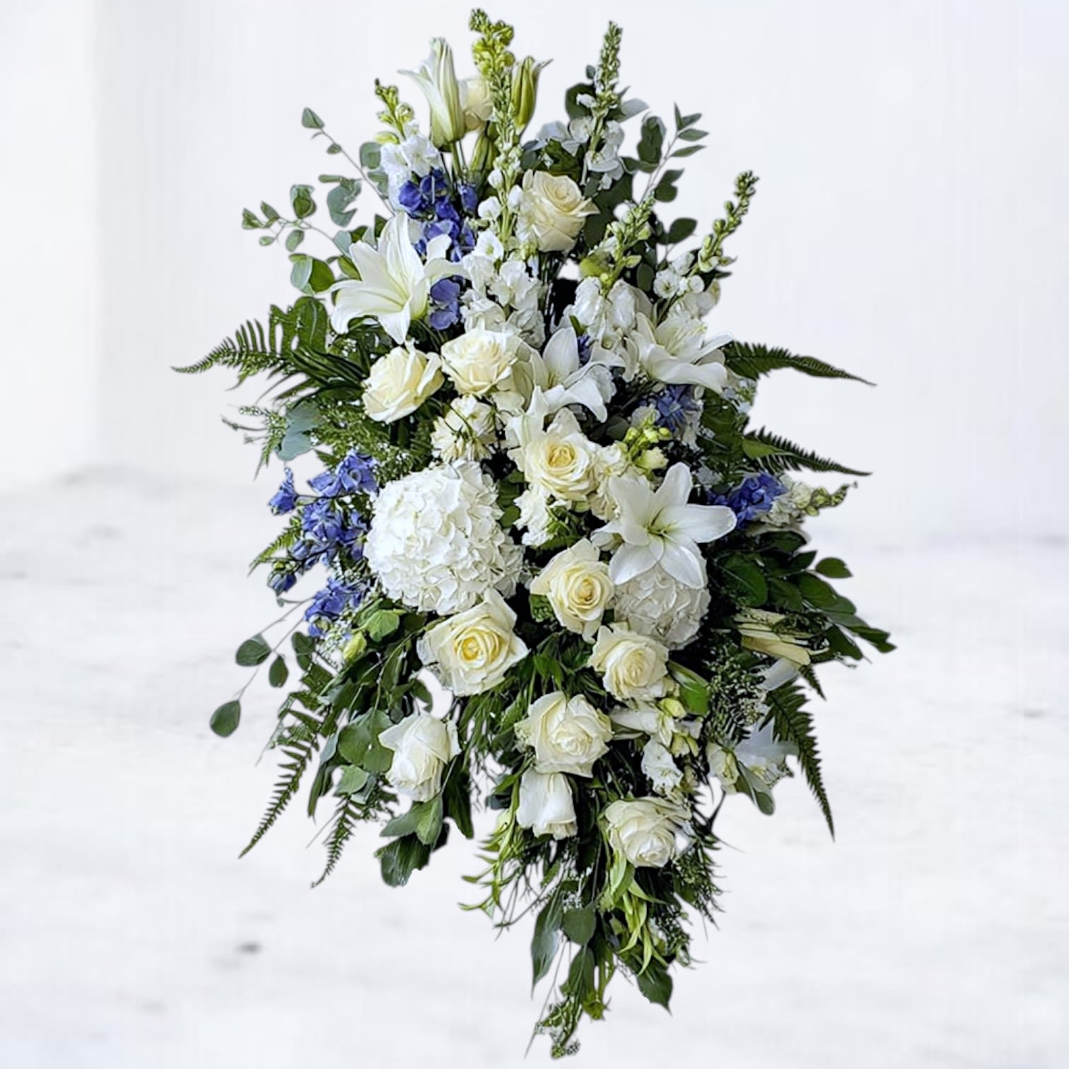 Peaceful Memories Standing Funeral Spray Peaceful Memories Standing Funeral Spray - The Peaceful Memories Standing Spray is a timeless expression of love and remembrance. Featuring classic ivory roses, elegant white lilies, lush hydrangea, and soft blue accents, this cascading design symbolizes purity, peace, and eternal devotion. Accented with fresh greenery, it brings comfort and honor to any funeral service, memorial, or graveside tribute. Available for same-day sympathy flower delivery in Houston and surrounding areas, the Peaceful Memories Standing Spray offers a heartfelt way to express your condolences.