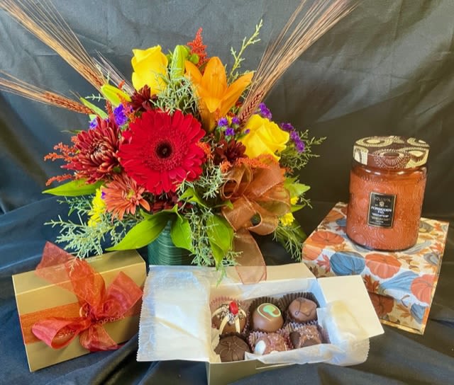 Hostess 3pc Gift Set - A floral arrangement designed in a cube with bright Fall colored flowers which is a perfect centerpiece for your hostesses table. This gift set includes a 6 piece box of assorted truffles and an 18oz Voluspa  Spiced Pumpkin Latte glass jar candle. (pumpkin gift box for photo purpose only, not included.)