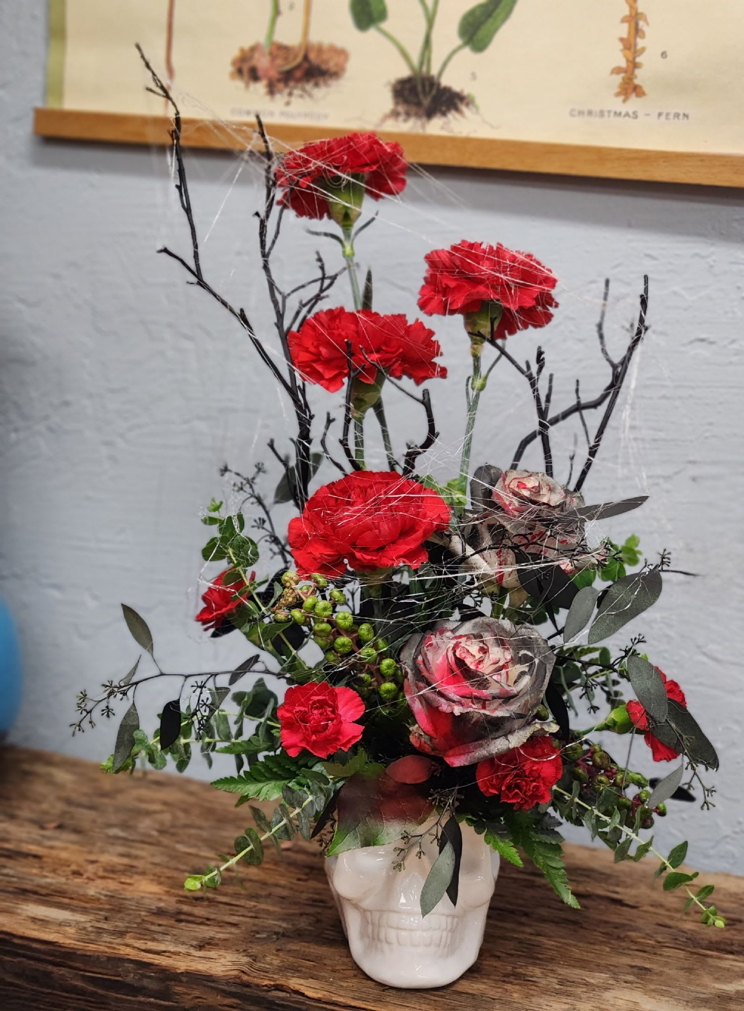 White Skully  - Cool white skull vase with black accents and deep red carnations. 