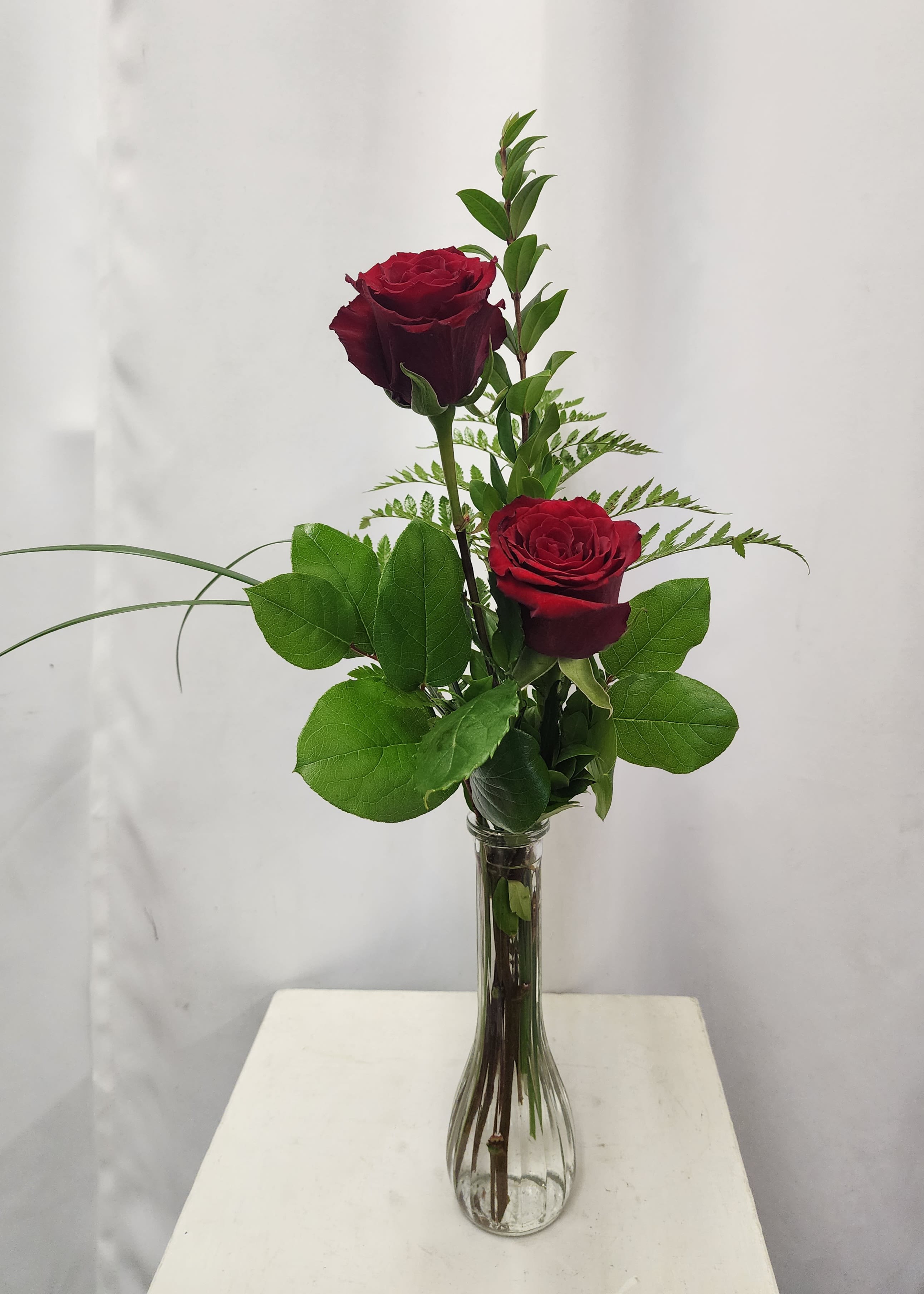 2 Roses in Bud Vase 2 Roses in Bud Vase - This simple and elegant arrangement features two fresh red Roses and greenery in a clear Bud Vase, perfect for any occasion. Choose from available Rose colors such as pink, white, yellow, or lavender. Please note color preferences in "notes to florist" when placing your order; based on availability.