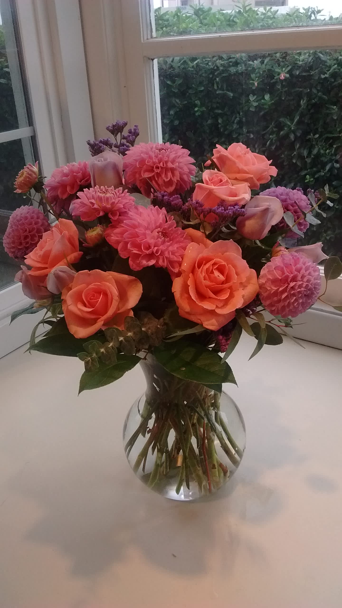 Coral Roses and Dahlias Coral Roses and Dahlias - Delicate roses (grown here in Oregon!) as well as locally grown dahlias are gathered in a curvy vase. Pinks, lavenders, and touches of bright coral make a bright statement.