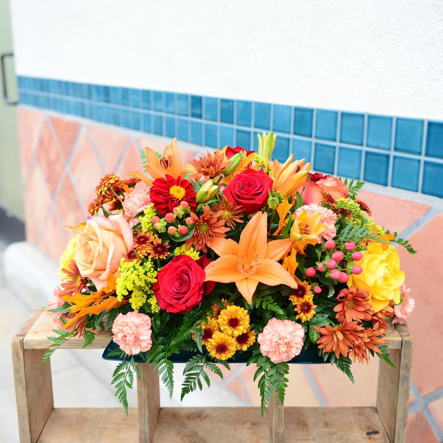 Fall centerpiece - A mix of all favorite flowers like roses, lilies, carnations, daisy, chrysanthemums in fall colors. Low container to can perfectly fit anywhere.