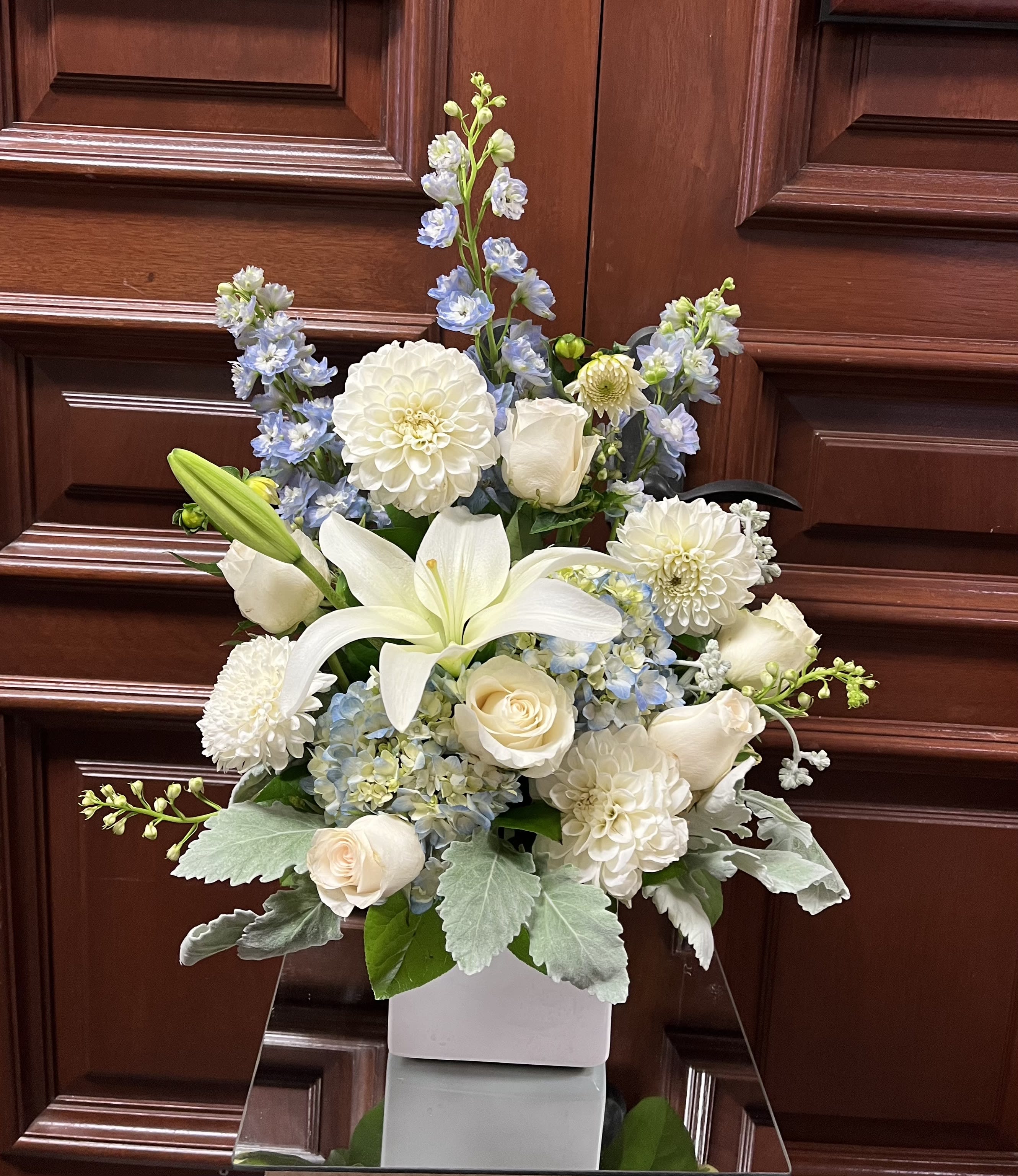 Love and Peace - Recipe: Blue Delphinium, White Seasonal Dahlias, White Casablanca Lilies, White Roses, Blue Hydrangeas and more in a square white vase. Availability: Seasonal Dahlias Design View: Symmetric Front Facing View Photo shown: Standard 