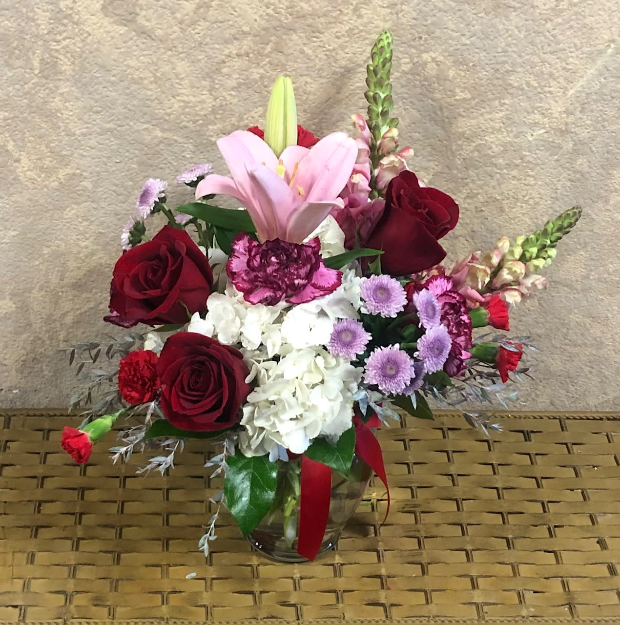 Regal Romance - Surprise Your Mom with This Special for Moms!  Type of Flowers: Pink Snapdragons, Red Roses, White Hydrangeas, Carnations, Mini Carnations, Purple Buttons in a vase with red ribbon. Availability: All year round Substitute Available: Yes Design View: Symmetric Front Facing View Photo shown: Regular 