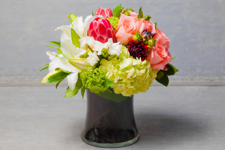 Fisherman's Wharf Welcome - A modern composition of dusty pink Roses, rhubarb red tropicals, heirloom tomato-red Dahlias and crisp white Lilies. 