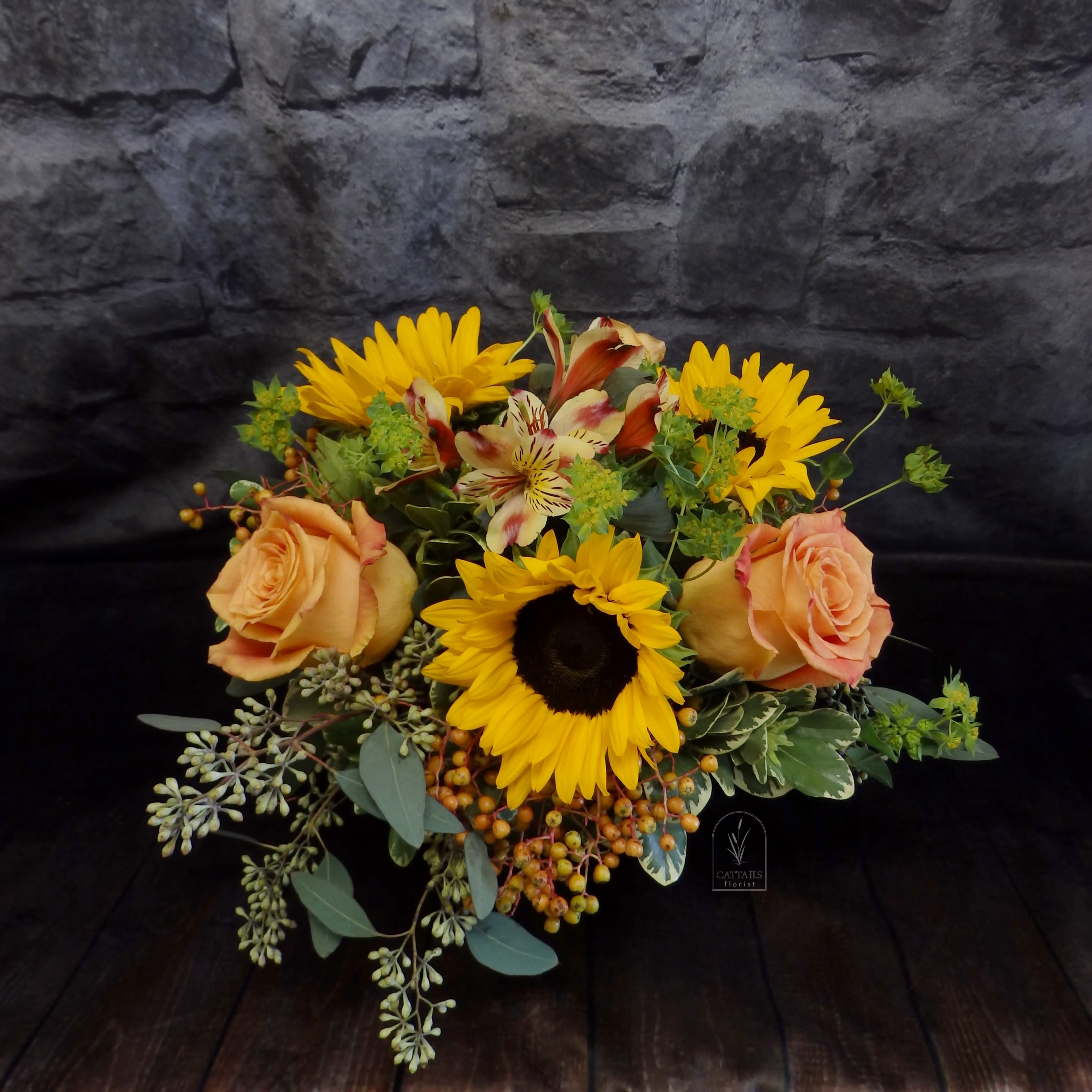 Amaretto Twist - “Amaretto Twist” is a cheerful fall bouquet featuring golden sunflowers, orange roses, and playful alstroemeria, accented with lush greenery and berry clusters  in a 4&quot; cube. A warm and inviting autumn arrangement, perfect for brightening any day. Available in Danville, CA.
