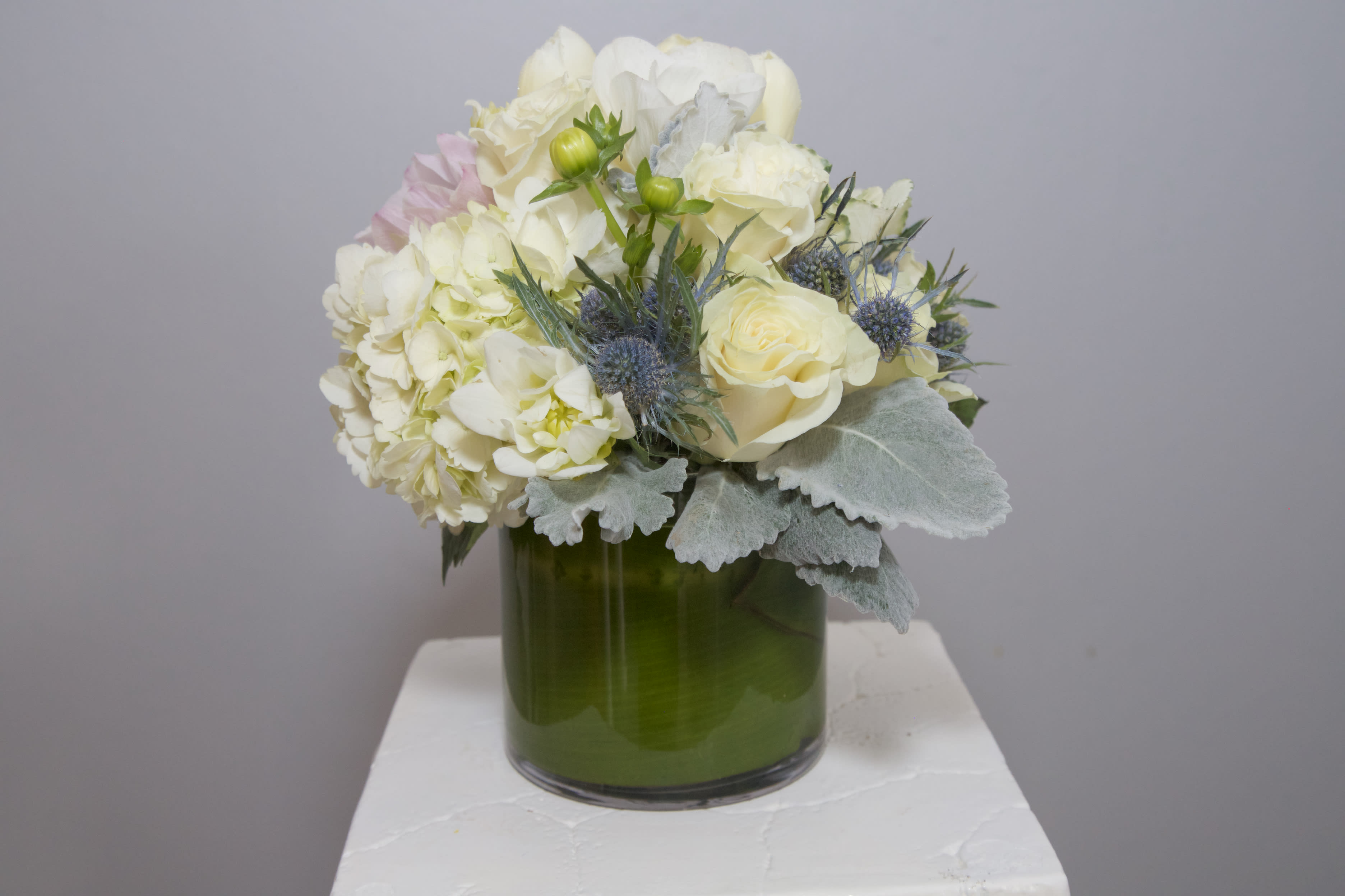 Polk Gulch Glam - A refreshing arrangement of Snow White Roses and Lilies, frosty succulents framed with seasonal greens and berries. 