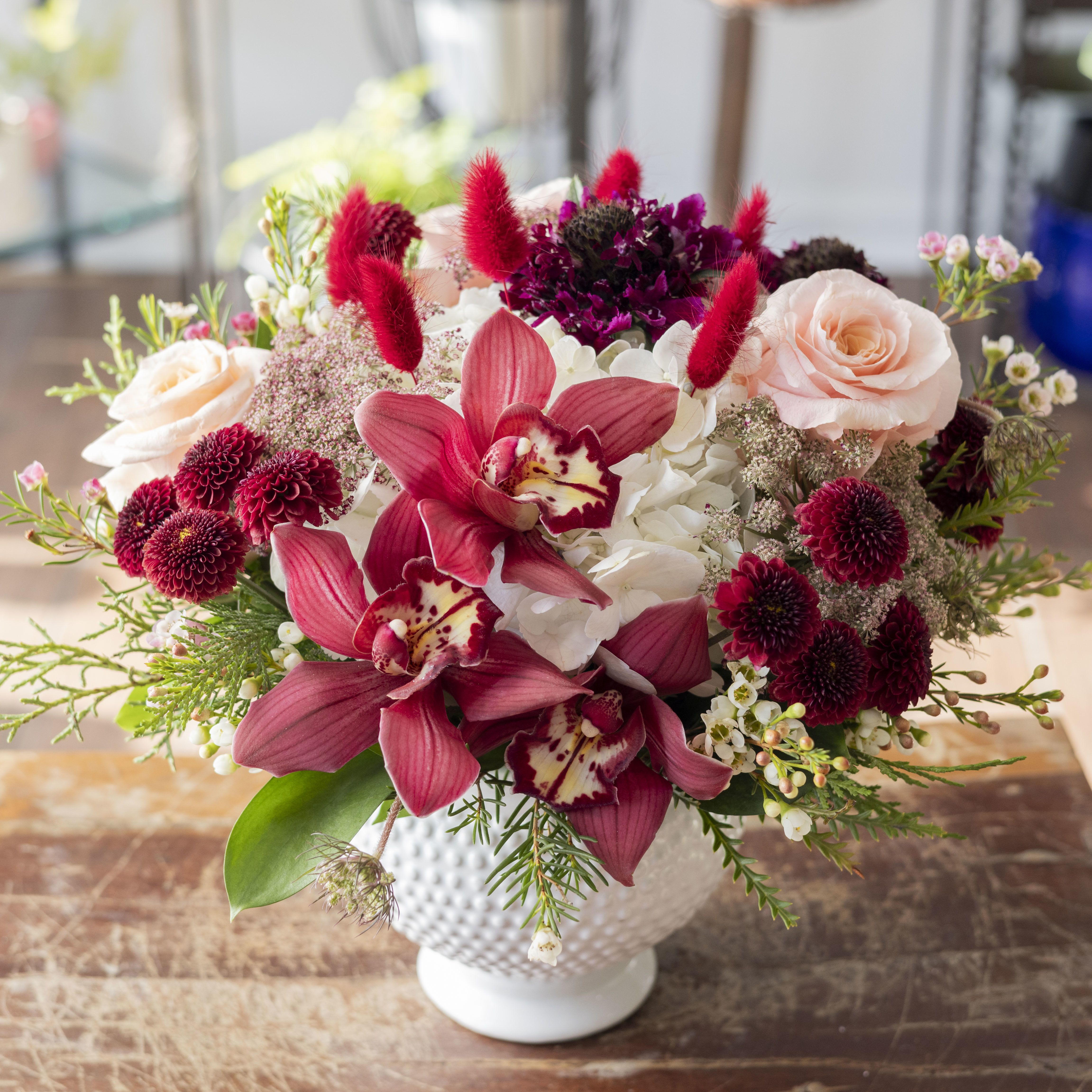 Aisha - Sweet, romantic assortment of flowers arranged in a short design within a textured ceramic vase. 