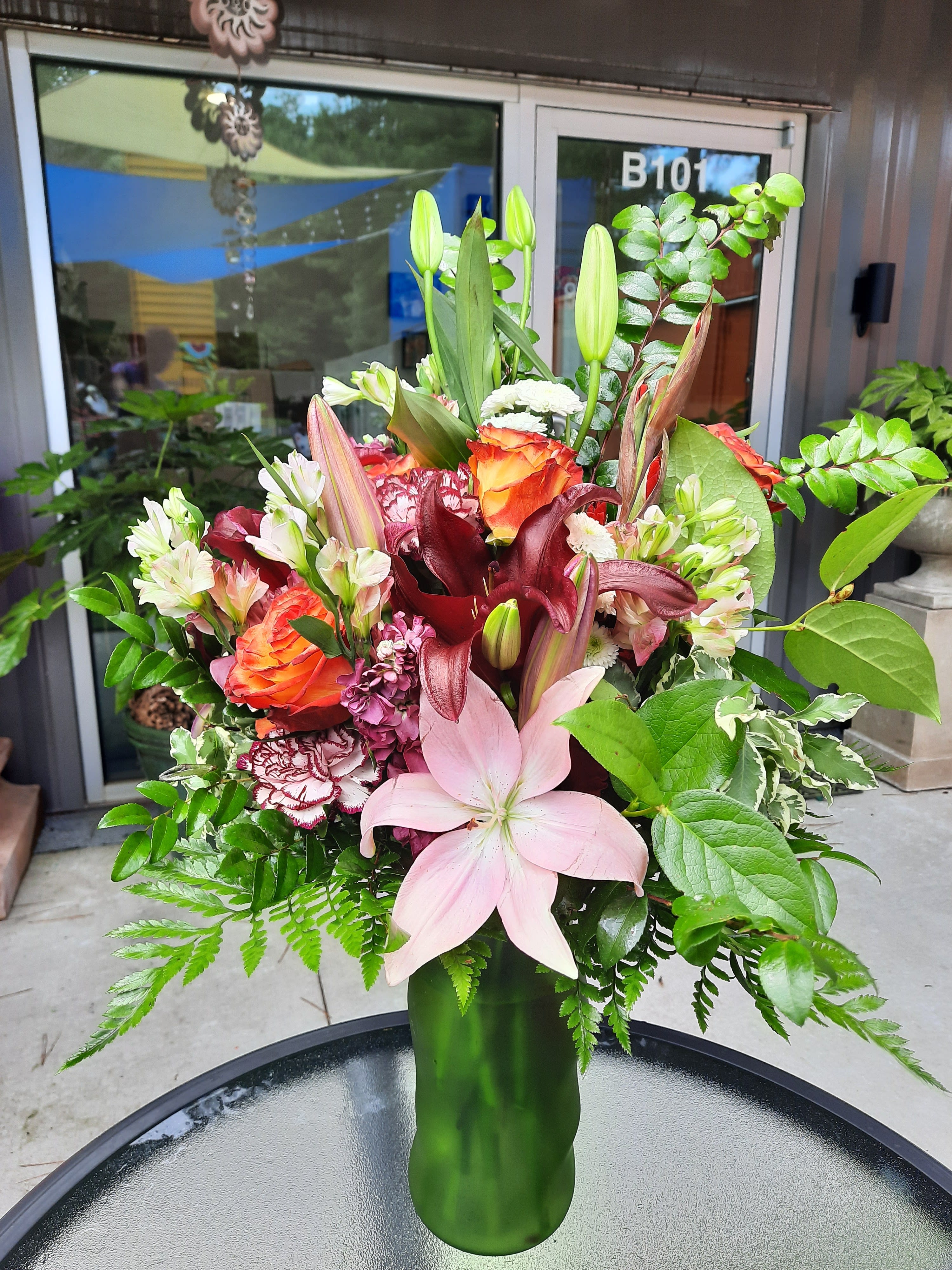  The Beautiful Buffet - Named for a lil' known soul food restaurant at the corner of Cascade and Fontaine. The Buffet is a splendid design with Hygrangea, red and pink lillies, stock, sunset roses, mixed carnations, white pom poms,pink Alstomeria, Huckleberry, salal, and leather leaf in a green colored vase. The arrangement pictured is a Premium.