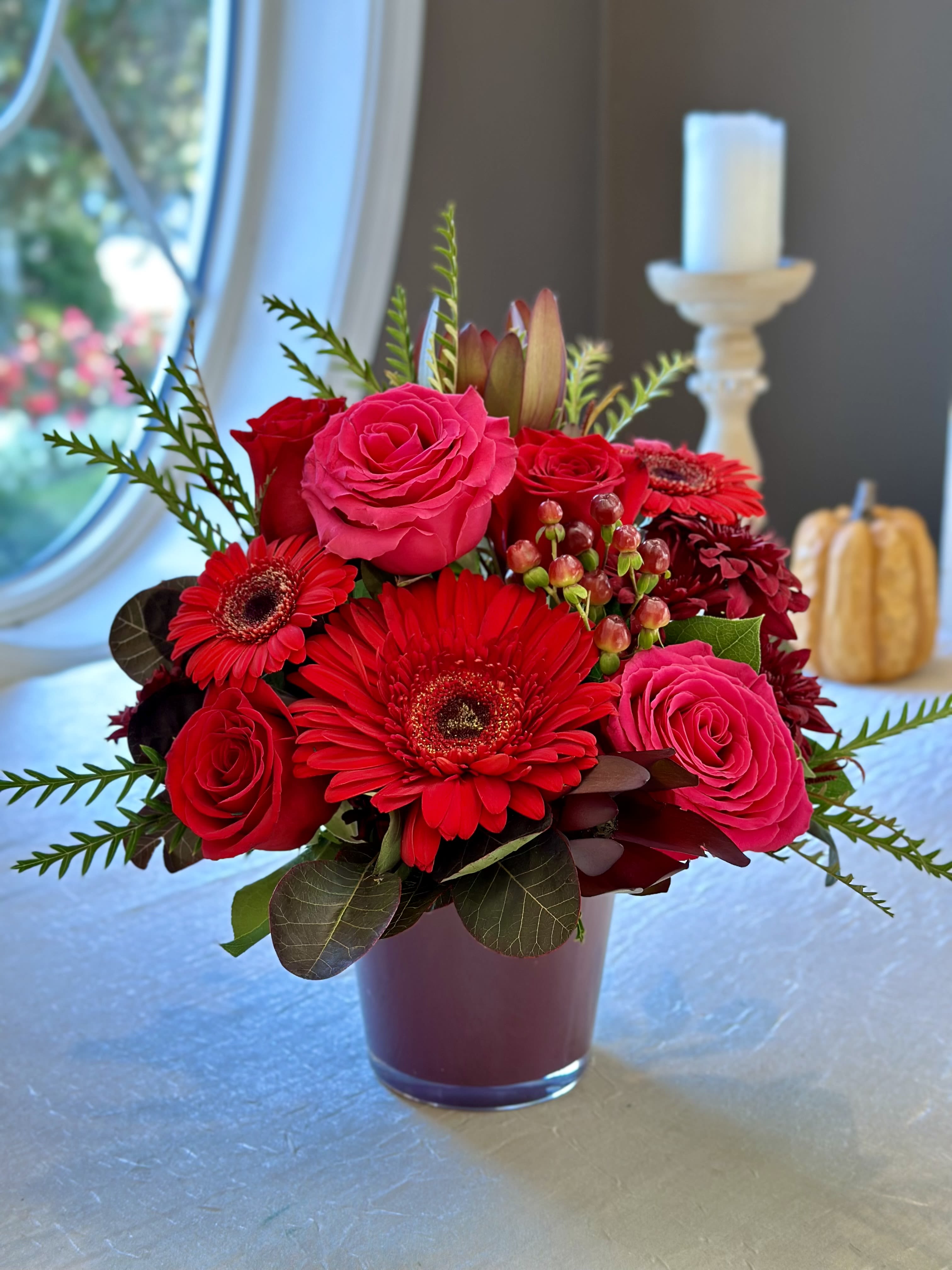 Harvest Sangria - LOCAL DELIVERY ONLY!!! Fall mix of fresh flowers that include gerbera daisy's, roses, berries, mixed greenery and mixed fall accents. Designed in a colored glass vase. FLOWERS AND COLORS MAY VARY!   AVAILABLE FOR LOCAL DELIVERY ONLY!!!