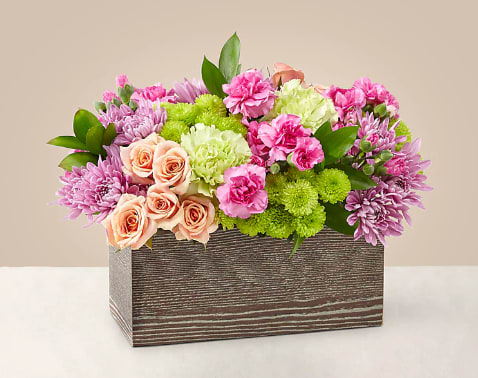 Simple Charm Bouquet Simple Charm Bouquet - Capture the beauty of the seasons in bloom with our Simple Charm Bouquet. Gorgeous blooms such as peach spray roses, green button pompon, pink mini carnations and lavender cushion pompons fill a weathered wooden box with freshness. Whether you're saying thank you to a special friend or sharing the most heartfelt get-well message, this arrangement is a breathtaking gift for your loved ones to cherish.