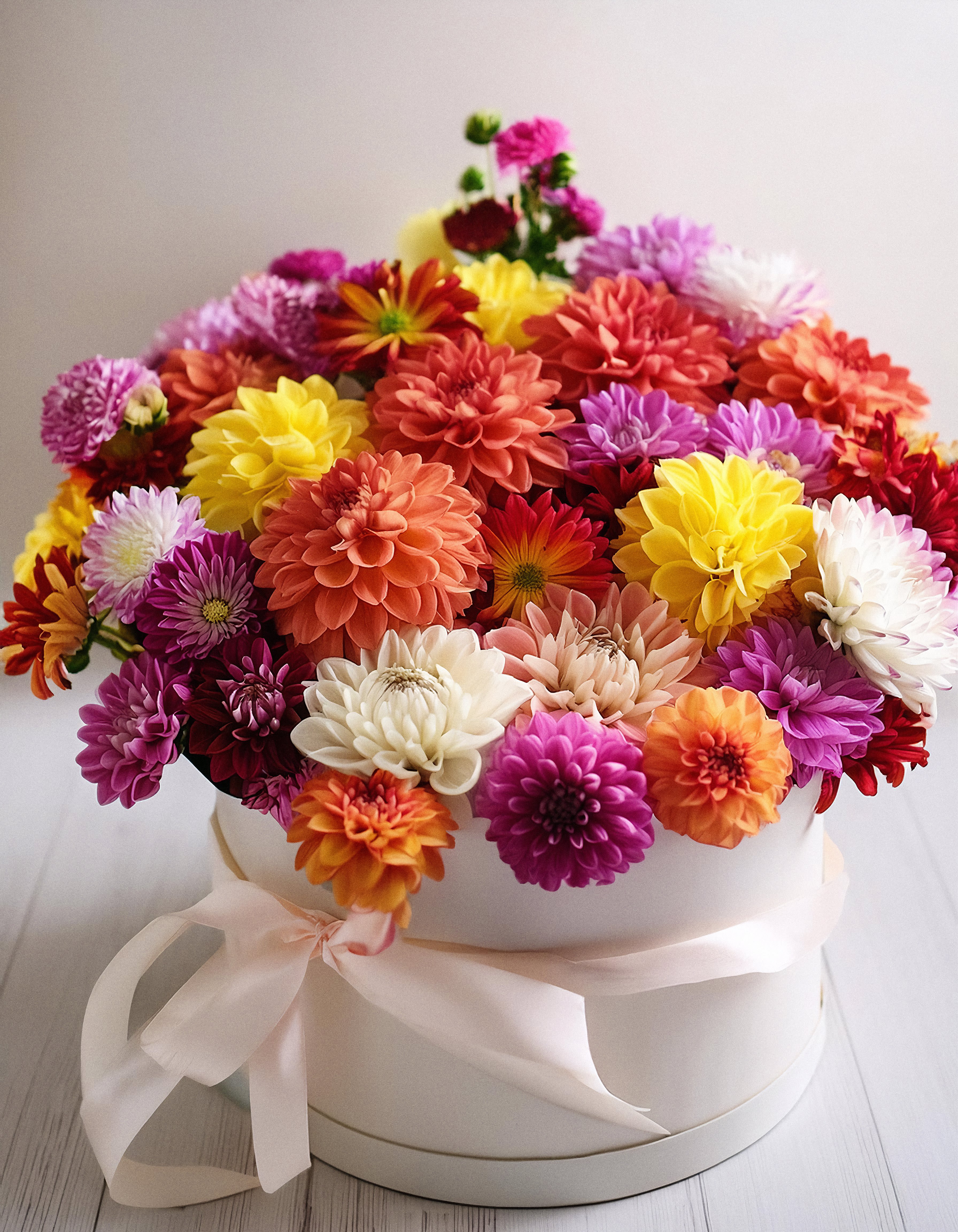 Colorful Fantasy  - Vibrant floral arrangement, beautifully displayed in a white hatbox. This stunning mix of dahlias in captivating shades of pink, orange, yellow, and purple. Eye-catching bouquet that exudes elegance and joy. Perfect for adding a splash of color to any occasion