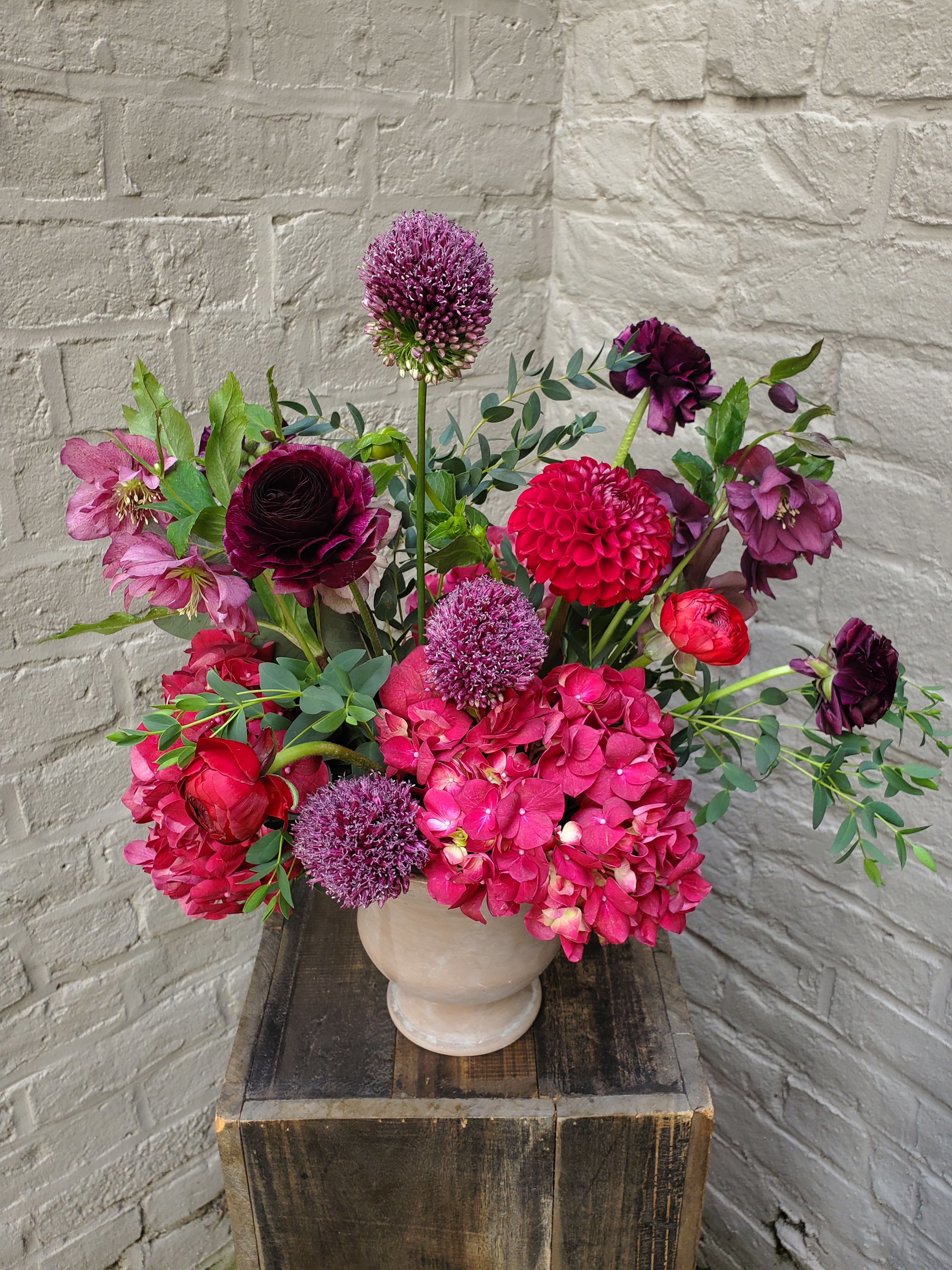 Equinox - An alluring blend of plush plum and velvety crimson blooms in a ceramic Tuscan compote -- including vibrant hydrangea, deep-hued ranunculus, and show-stopping dahlias.  Standard arrangement measures approximately 16&quot;x16&quot;.