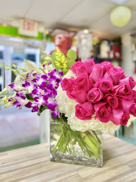 Rose Cluster and Orchids Flowers - Hot Pink - Rose Cluster and Orchids Flowers: Trendy and elegant arrangement with a bundle of roses, callas lilies, orchids, greens, fillers, and hydrangeas in a large cube vase accented with stones/crystals and a personalized greeting card.
