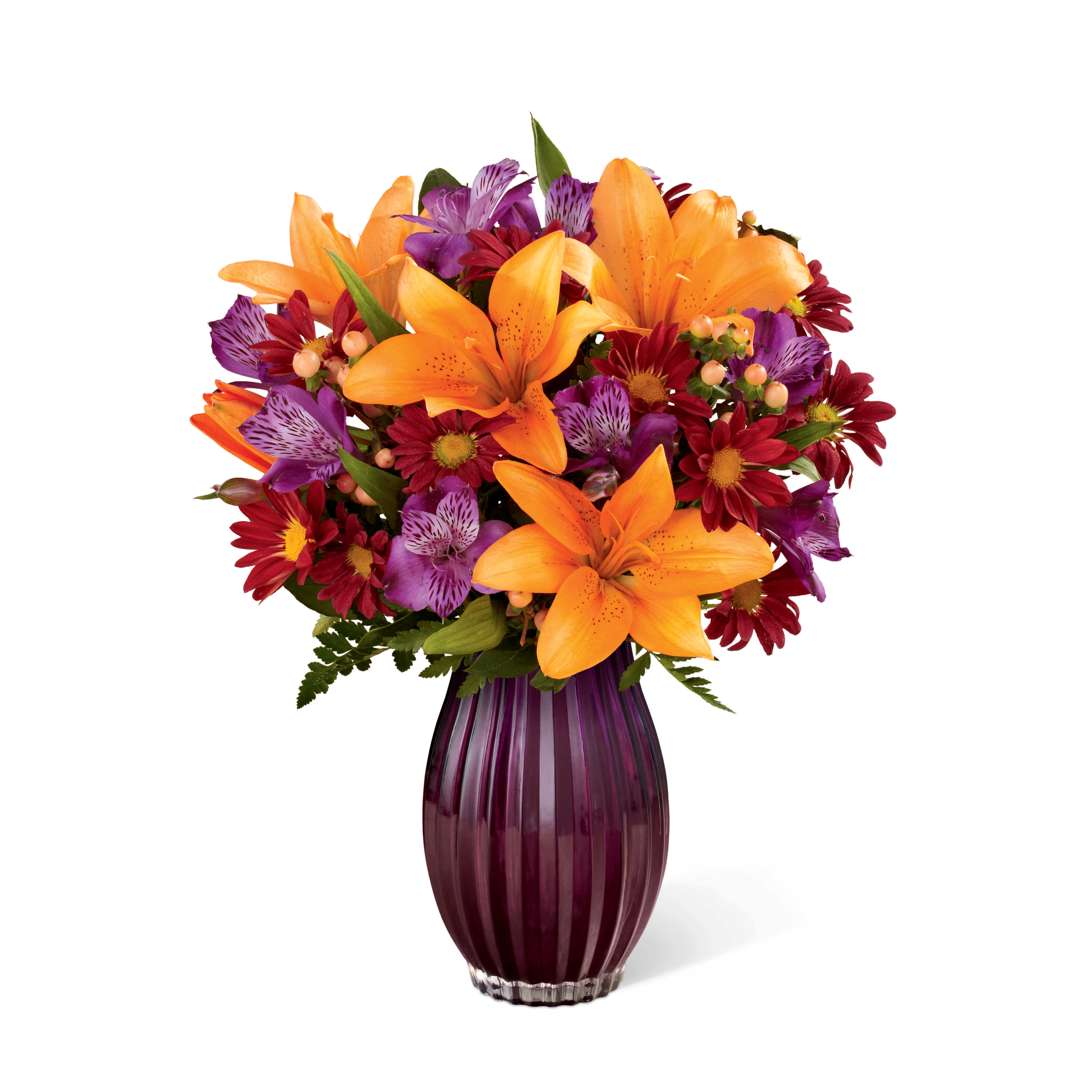 The FTD® Autumn Splendor® Bouquet - Item Number: 15-F5s  Taking a sophisticated approach to autumn beauty, this elegant arrangement captures the breathtaking drama and fantastical beauty of a brilliant autumn sunset. Creating a harmonious counterpoint of twilight colors, it combines sun-drenched orange Asiatic lilies and subtle peach-colored Hypericum berries that “pop” among the lavender roses and purple Peruvian lilies and daisy pompons. Beautifully arranged in a ribbed, plum-colored glass keepsake vase, it brings a whole new excitement to any gift giving occasion this season.
