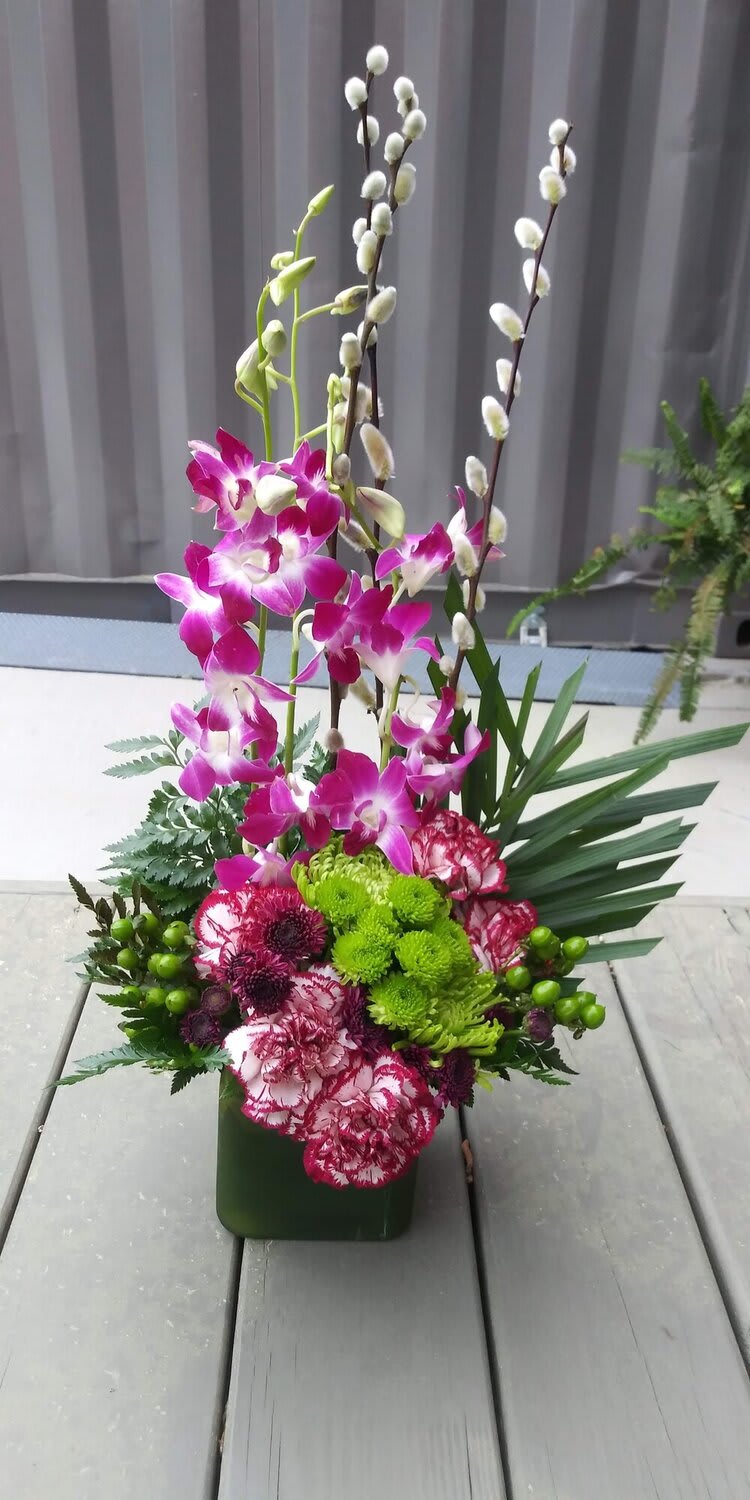 SCAD Planter - Creative roots run deep in Atlanta, and the SCAD Planter by Royal Petals ATL is a living homage to the visionary energy of SCAD’s Atlanta campus. Nestled in the heart of Midtown, SCAD Atlanta is where bold design, cultural expression, and innovation flourish—and this artfully curated planter captures that spirit in bloom.  Designed with an eye for form, color, and movement, the SCAD Planter features a dynamic mix of sculptural greenery, architectural and vibrant florals. A modern mix of orchids, carnations, green poms, pussy willow, green hypericum, and assorted greens in a tray planter. Each plant reflects the diverse disciplines taught within SCAD’s inspiring Peachtree Street hub—fashion, animation, interior design, and fine arts—all growing together in harmony, much like the students who pass through its glass-walled studios.  The container itself often takes cues from modern art and industrial design, echoing the creative aesthetic of SCAD show, the Hive residence halls, and the sleek urban backdrop of Atlanta’s creative corridor. It’s more than a gift—it’s a desktop ecosystem of inspiration, perfect for dorms, design studios, or gallery-style living spaces.  Whether celebrating a graduation, welcoming a new student, or gifting a creative soul, the SCAD Planter brings a piece of Atlanta’s artistic pulse into everyday life—rooted in beauty, thriving with purpose.
