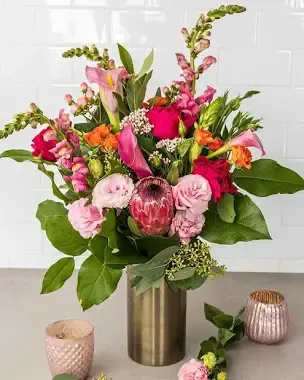 Sun & Roses Sun & Roses - Bright sunflowers, golden roses, and soft white blooms are gathered with fresh greenery in a charming embossed vase, radiating warmth and cheer.