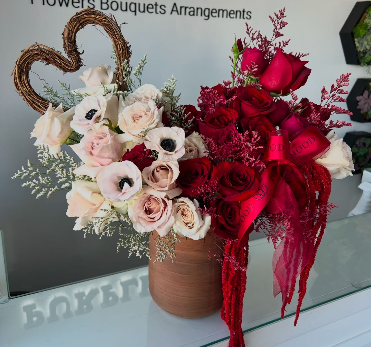 Heart Vase Heart Vase - The Heart Vase is a stunning expression of love and passion. With soft blush tones on one side and bold reds on the other, it symbolizes two hearts coming together as one. Styled in a chic vase and finished with elegant details, it’s the perfect gift for anniversaries, Valentine’s Day, or any romantic occasion.  Key Features:     •    Striking two-tone design with blush and deep red blooms     •    Styled in a modern vase with heart accent detail     •    Finished with elegant ribbons for a romantic touch     •    Available in Standard ($215) and Deluxe ($285) sizes     •    A meaningful gift to celebrate love and devotion