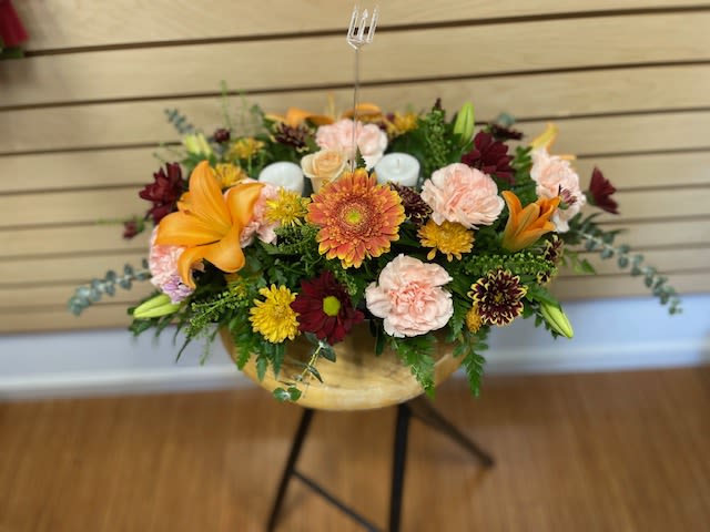 Fall Table Centerpiece - Fall centerpiece with mixed flowers and candles. The arrangement contains orange lilies, white candles, fall colored daisies, and peach carnations.