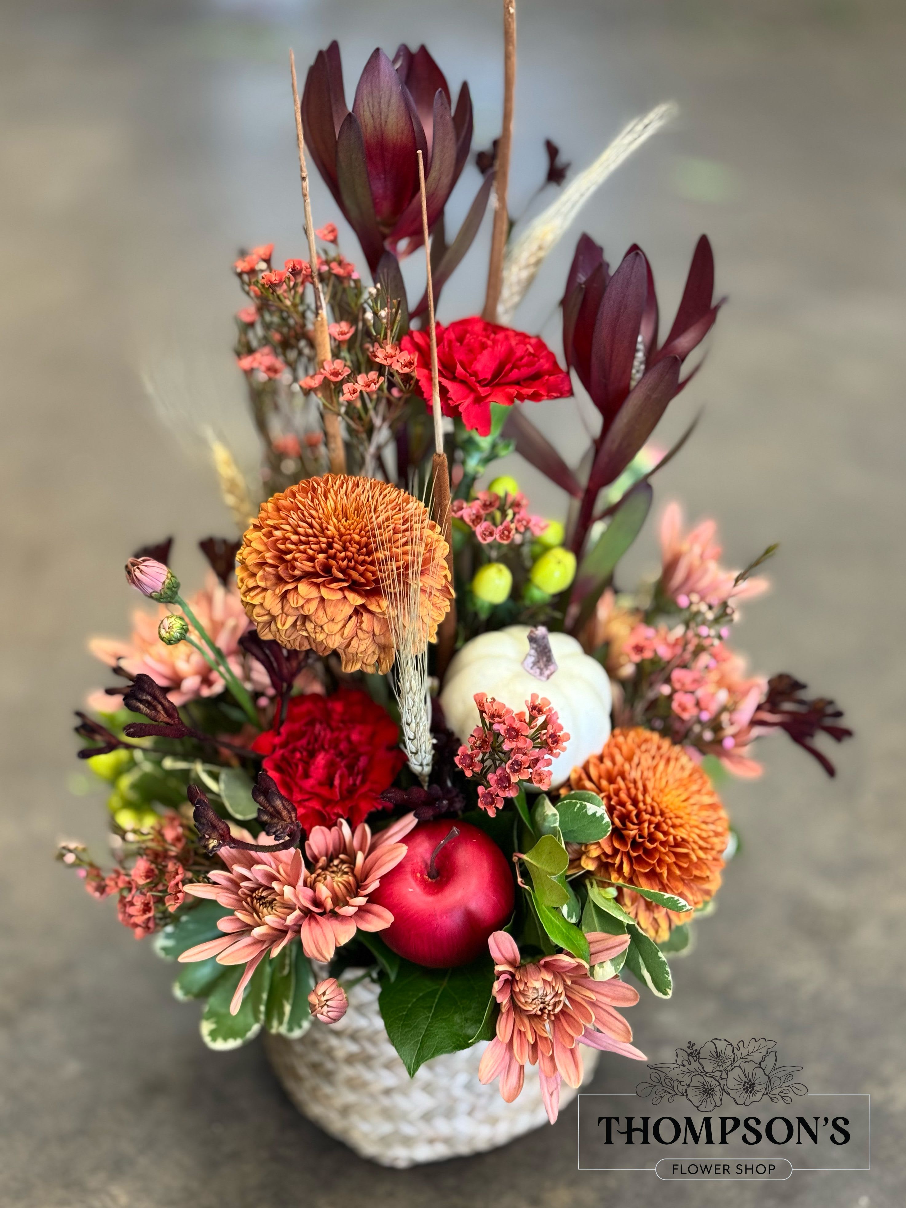 Rustic Autumn Gathering - Handcrafted by Thompson’s Flower Shop, Rustic Autumn Gathering blends bronze mums, carnations, daisies, and rich foliage with seasonal textures like wheat, cattails, a pumpkin, and apple accents. Designed in a woven basket, this festive favorite is available for same-day flower delivery in Peoria, Surprise, Goodyear, and across the West Valley — a beautiful choice for Thanksgiving or fall celebrations.