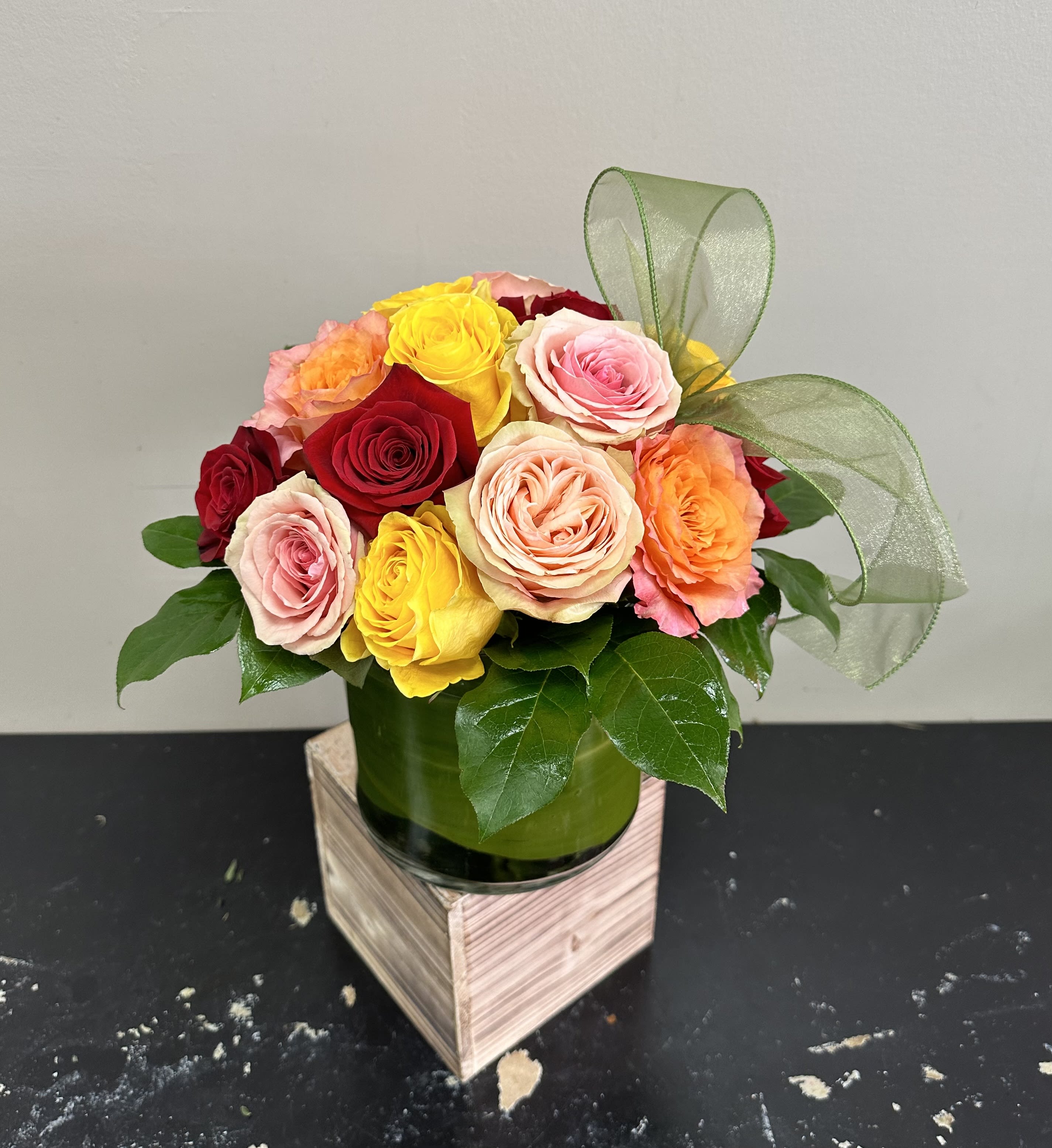 Starburst  Starburst  - A dozen assorted roses in a modern styled shorter vase with greenery around the sides. These roses are the perfect gift for anniversaries, birthdays, retirement, or even just because! Order for a same day or next day delivery and give us a call if you want custom flowers.