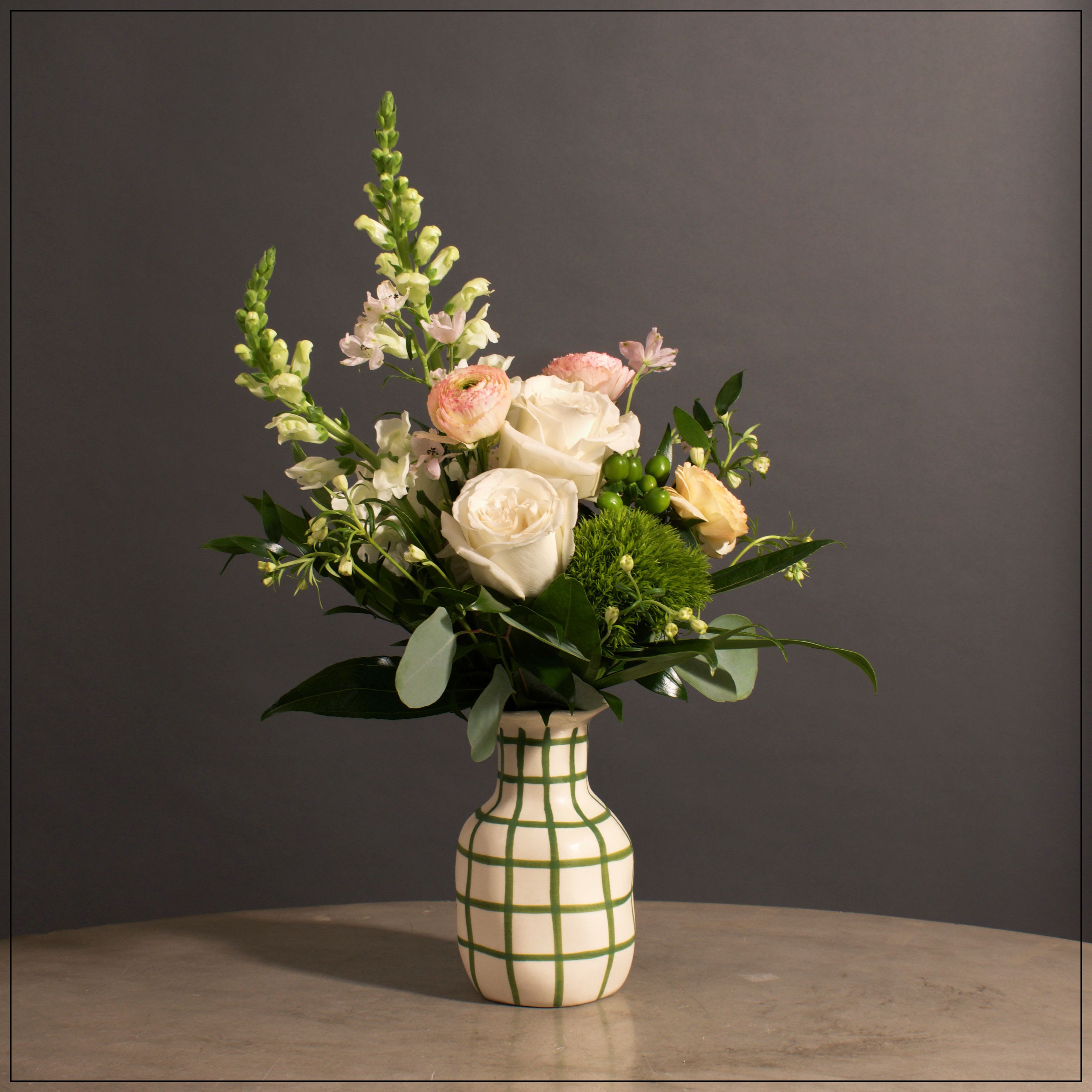 Savannah Savannah - Modern white and green vase filled with a lovely mix of snap dragons, roses, ranunculus, hypericum, and delphinium. Approximately 19" tall and 16" wide
