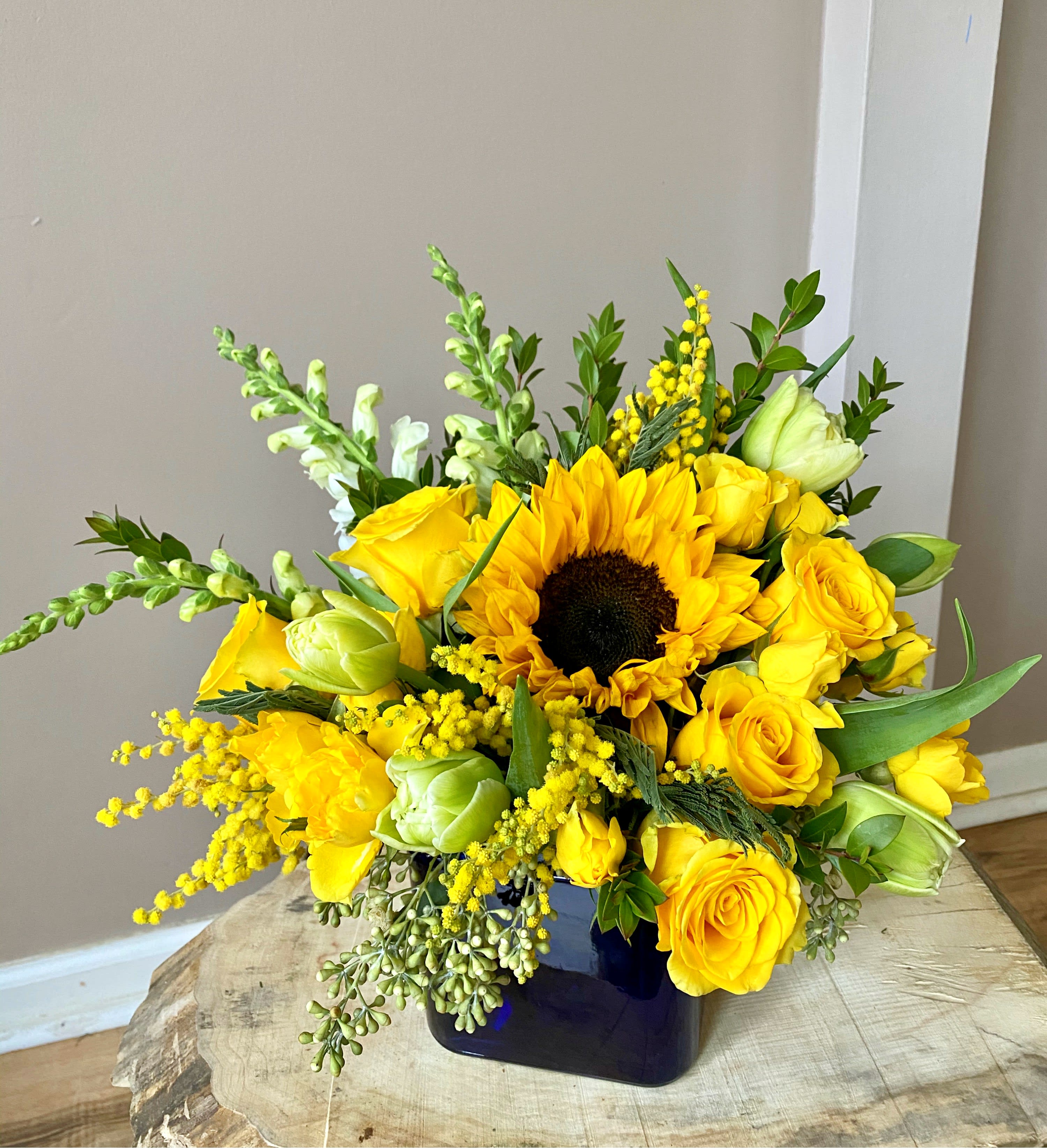 Vitamin D for your Soul - This bright flower arrangement is like a mini Sun in a vase! It will bring a smile to one's heart, guaranteed! If someone is struggling with life's unexpected turns, send this arrangement to cheer them up and show how much you care. If your loved one is celebrating the beauty of life - send this sunny arrangement to hug the Soul!   * Yellow roses and spray roses * White/yellow snapdragon * Tulips - the color may vary due to availability (green, white or yellow) * Sunflower * Filler flowers - in the pictured arrangement we've used Acacia (commonly known as Mimosa, small flowers in clusters) which are seasonal flowers available during Spring months and in other months might be substituted with different flowers, such as waxflower.  * Greenery - Eucalyptus and/or myrtle  - Flowers are arranged in dark blue glass vase.  We put a piece of our Soul to every single arrangement we make. Here at Soul's Greenhouse, we strive for fresh, high-quality florals and flower designs, in the Fox River Grove, Cary, Crystal Lake, Barrington, Algonquin, and surrounding areas. We aim for quality, unforgettable service, and the best value for our customers! Let us take care of all your flower needs. We promise our flowers will hug your heart!   