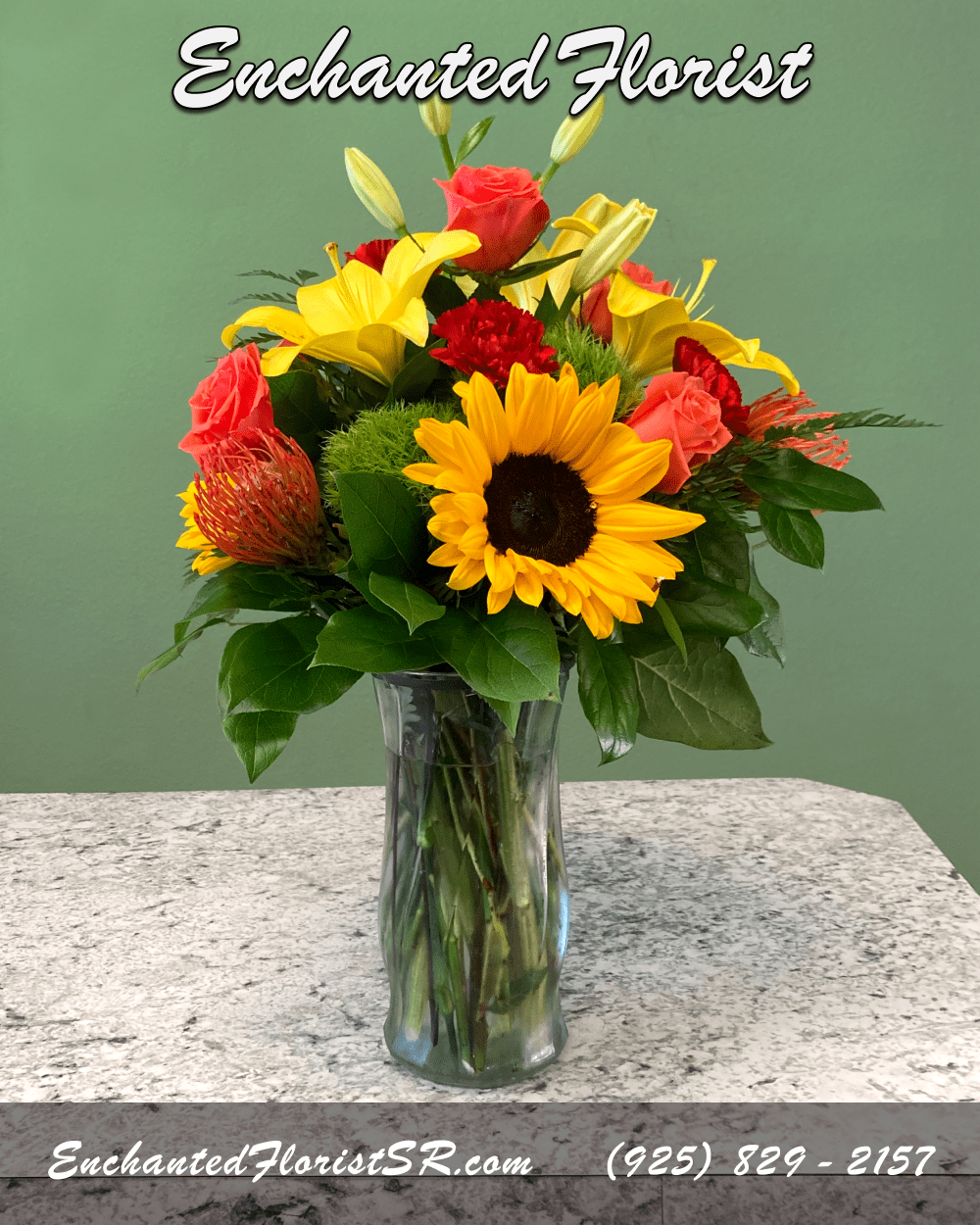 Beaming - Mixed Arrangement - A spirited mixed arrangement showcasing vibrant shades of red, orange and yellow. Featuring an array of premium blooms including roses, sunflowers, asiatic lilies, carnations, and 'pincushion' proteas. Accented with verdant 'trick' dianthus, lush lemon leaves, and leather ferns. Presented elegantly in a 'crystal' clear glass rose vase.   This vibrant mixed arrangement is perfect for brightening someones day, or adding a pop of color to any room.  Arrives In: Clear glass cylindrical vase  Orientation: Any-Sided  Approximate Dimensions: 16&quot; Tall 10&quot; Wide 8.75&quot; Vase Height